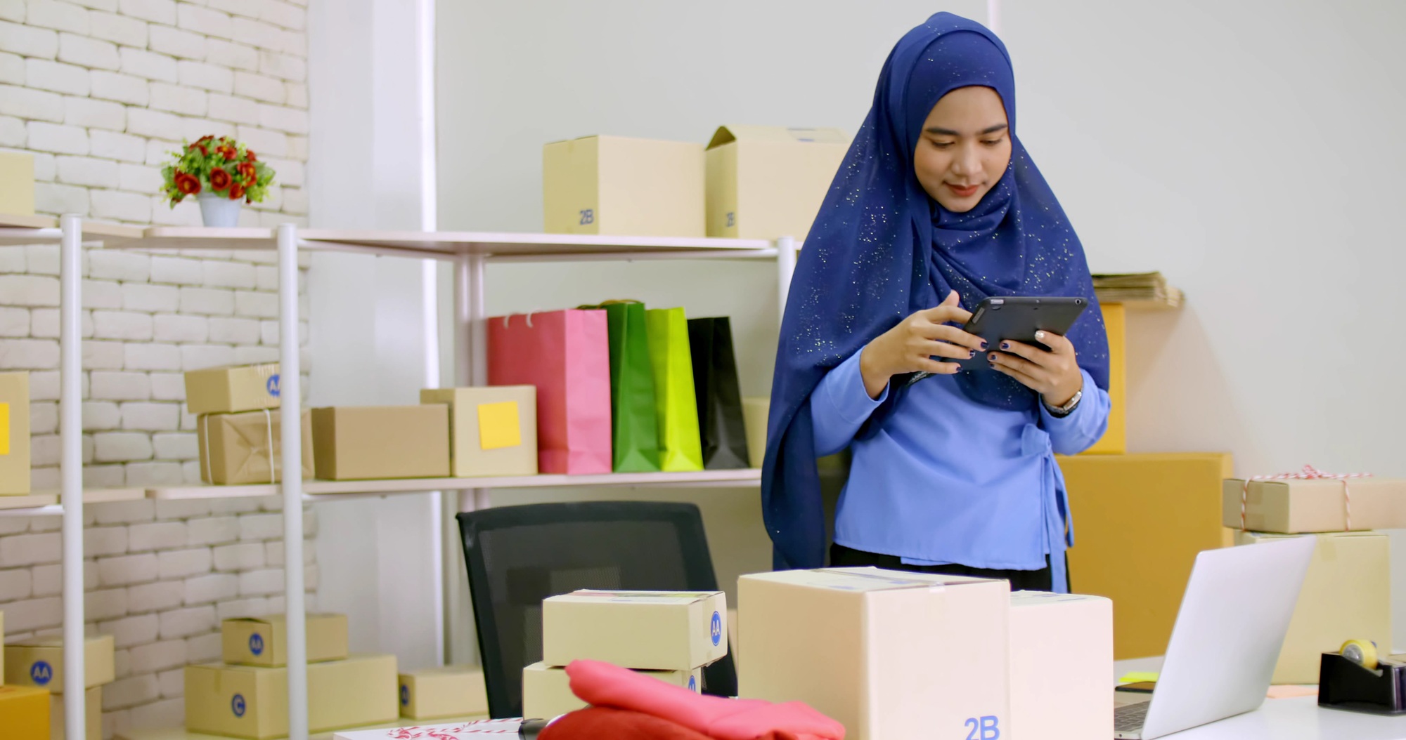 Beautiful muslim female merchandiser doing online marketing at the office.