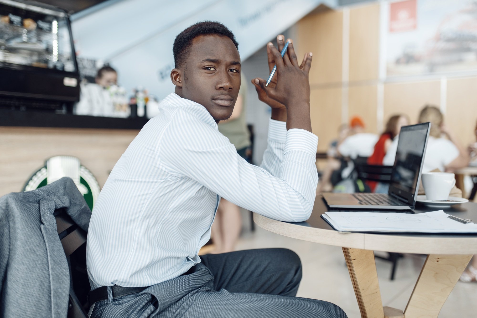 Black businessman at laptop in car dealership