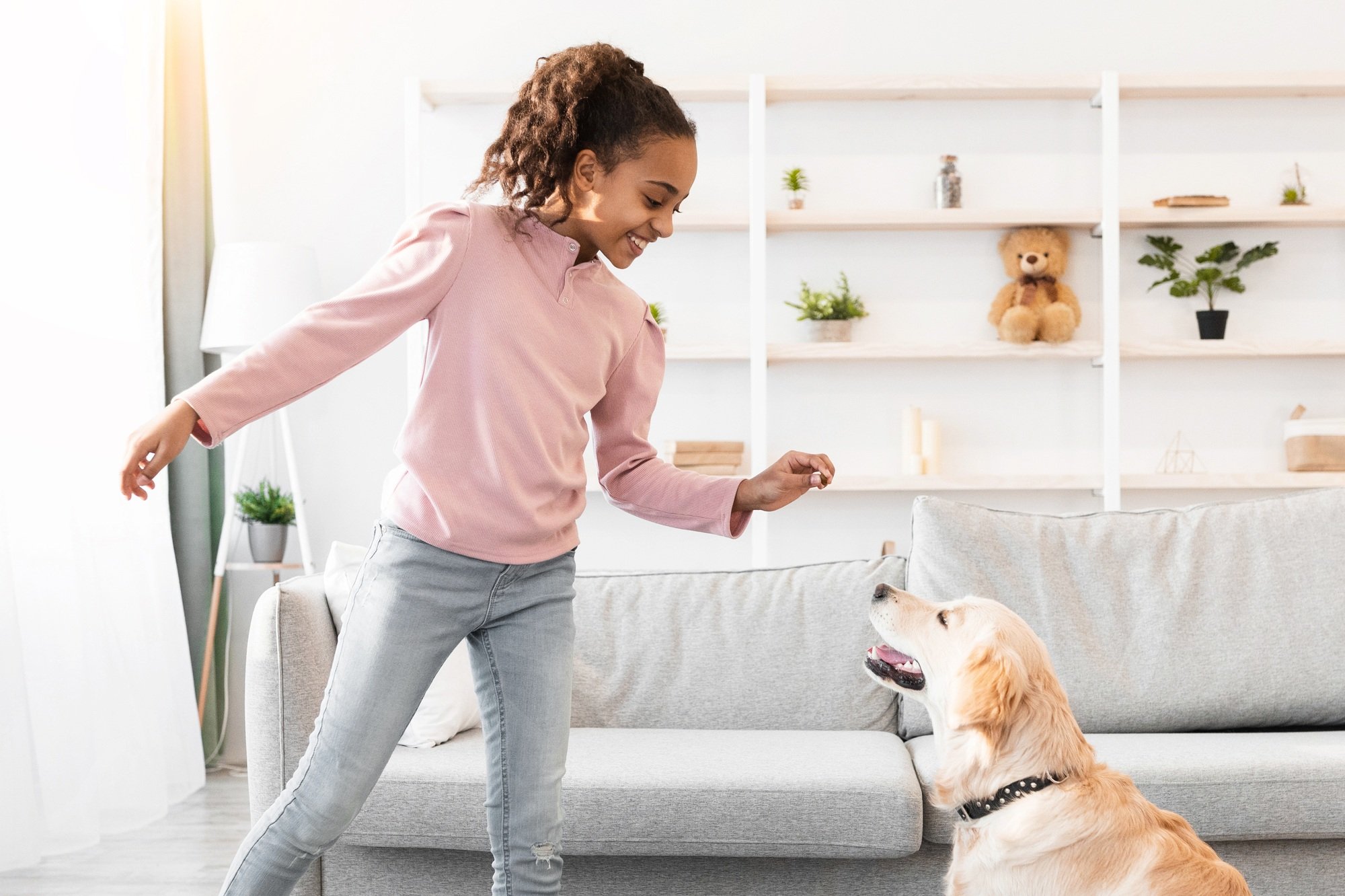 Black girl training and giving treat to her obedient dog