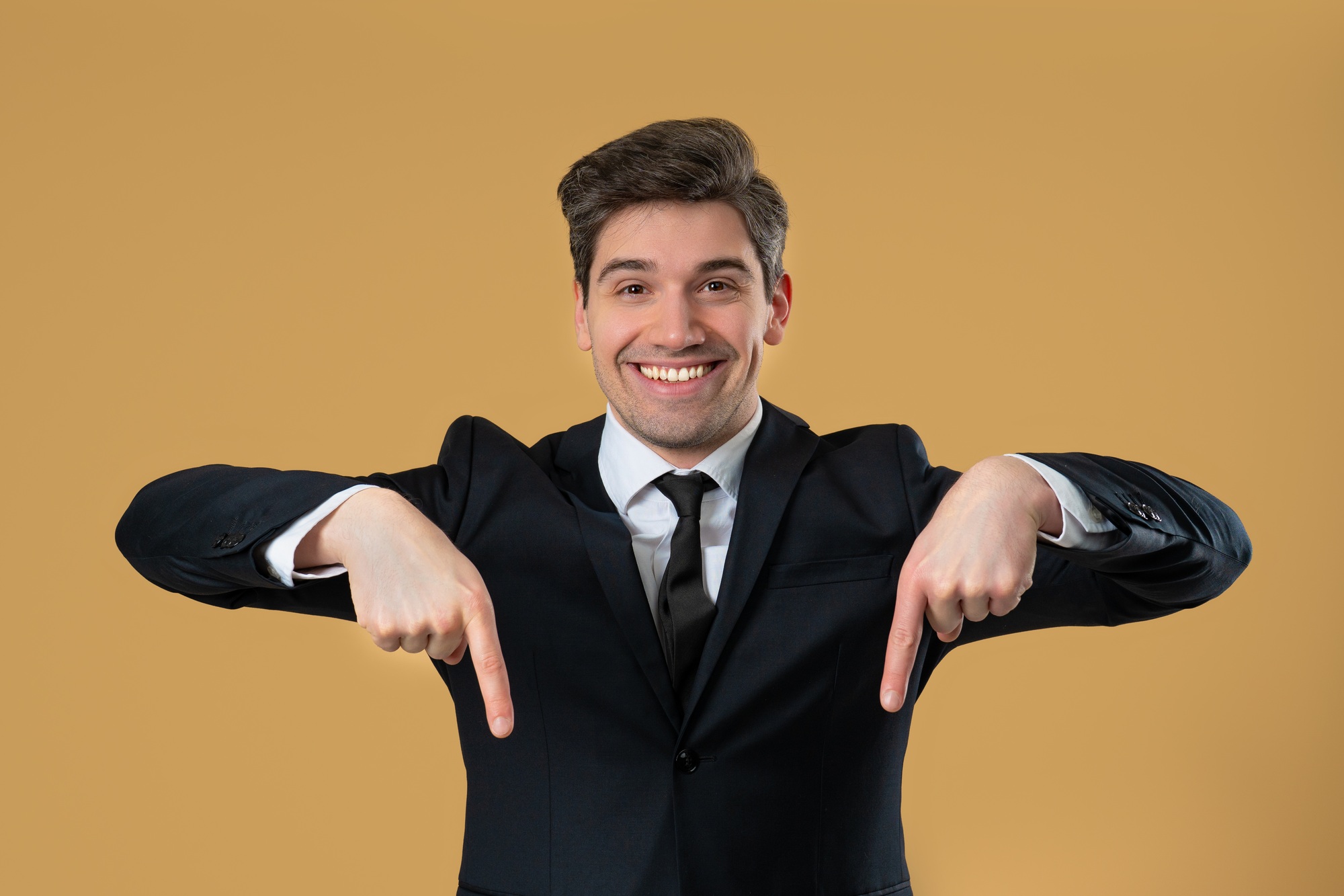 Blogger Businessman Pointing Down Advertising Area. Beige Wall. Click, Subscribe