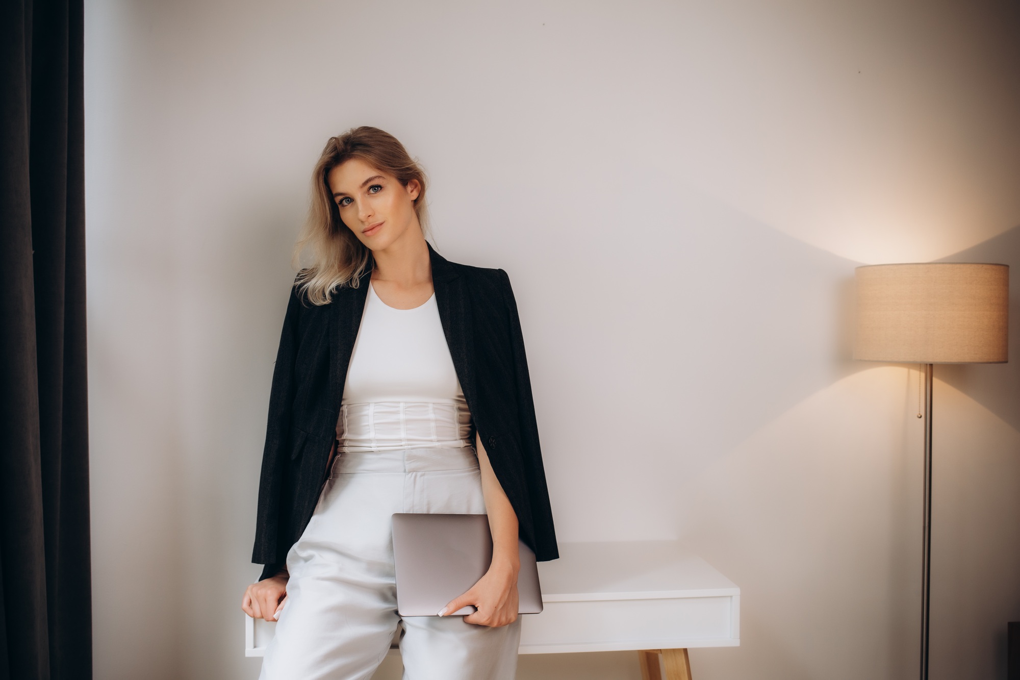 blonde in a black jacket with a laptop in the office