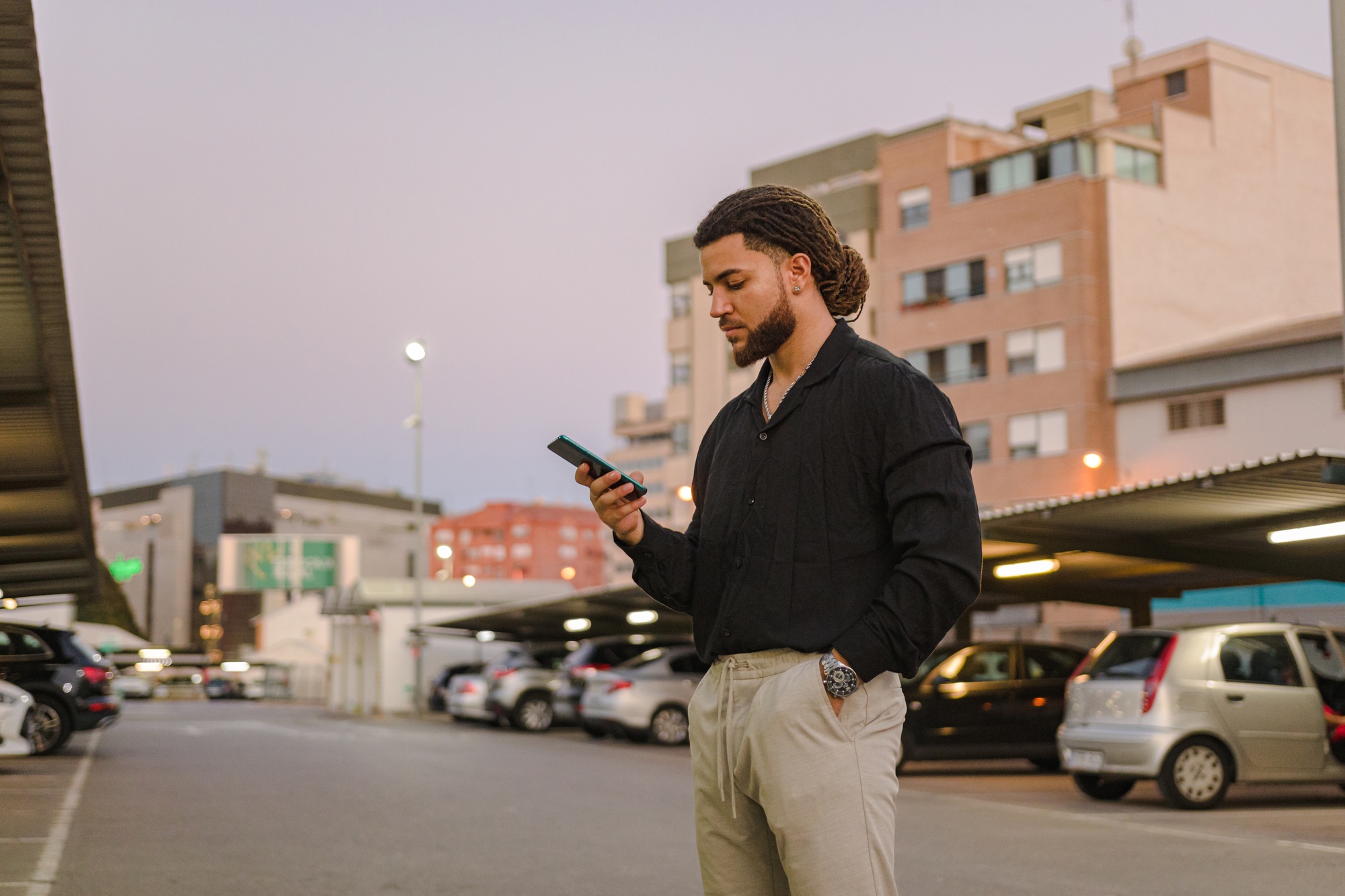 Business Latin man with a phone in a parking lot