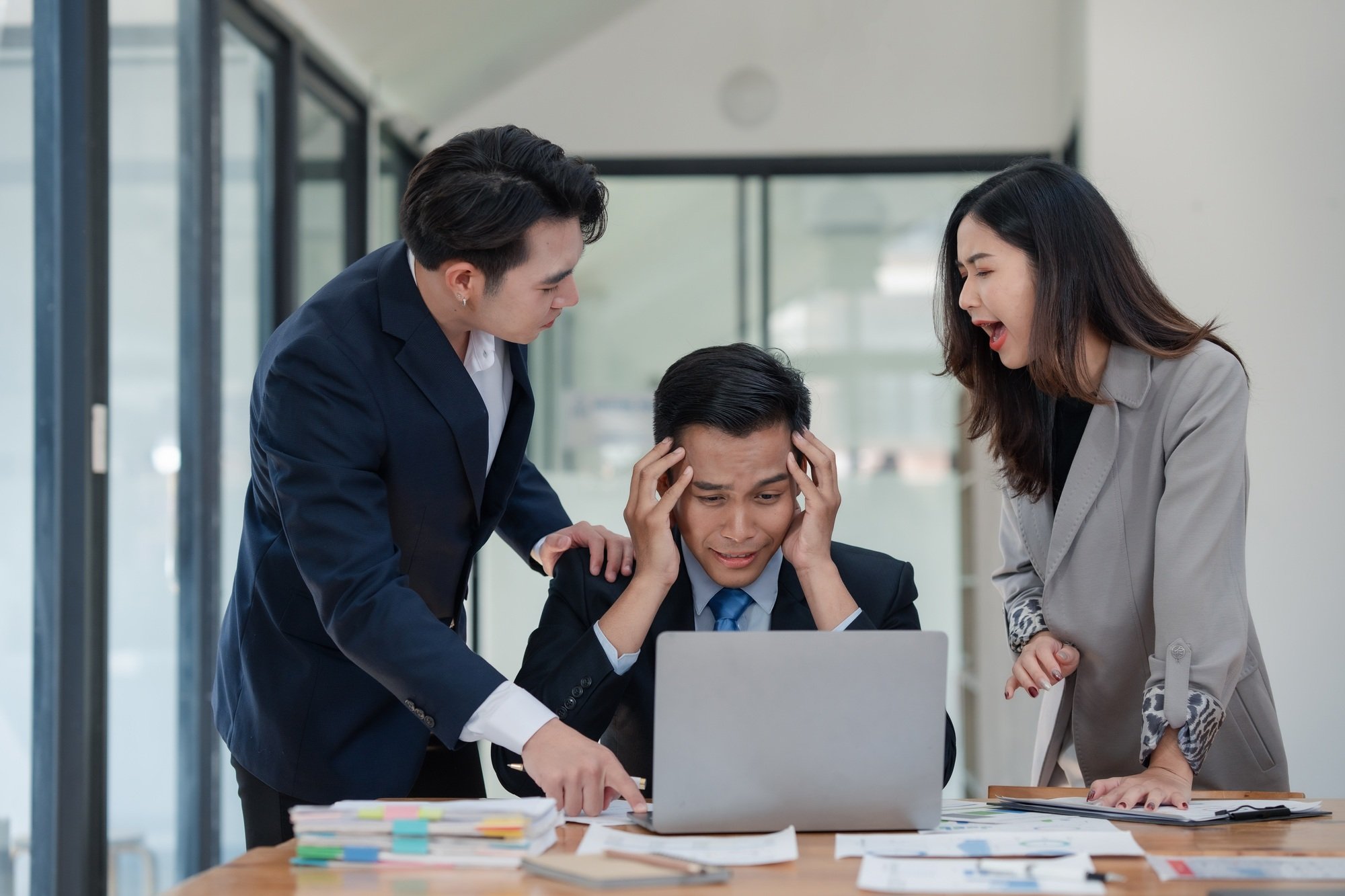 Business team in office environment experiencing stress and conflict, with a frustrated man