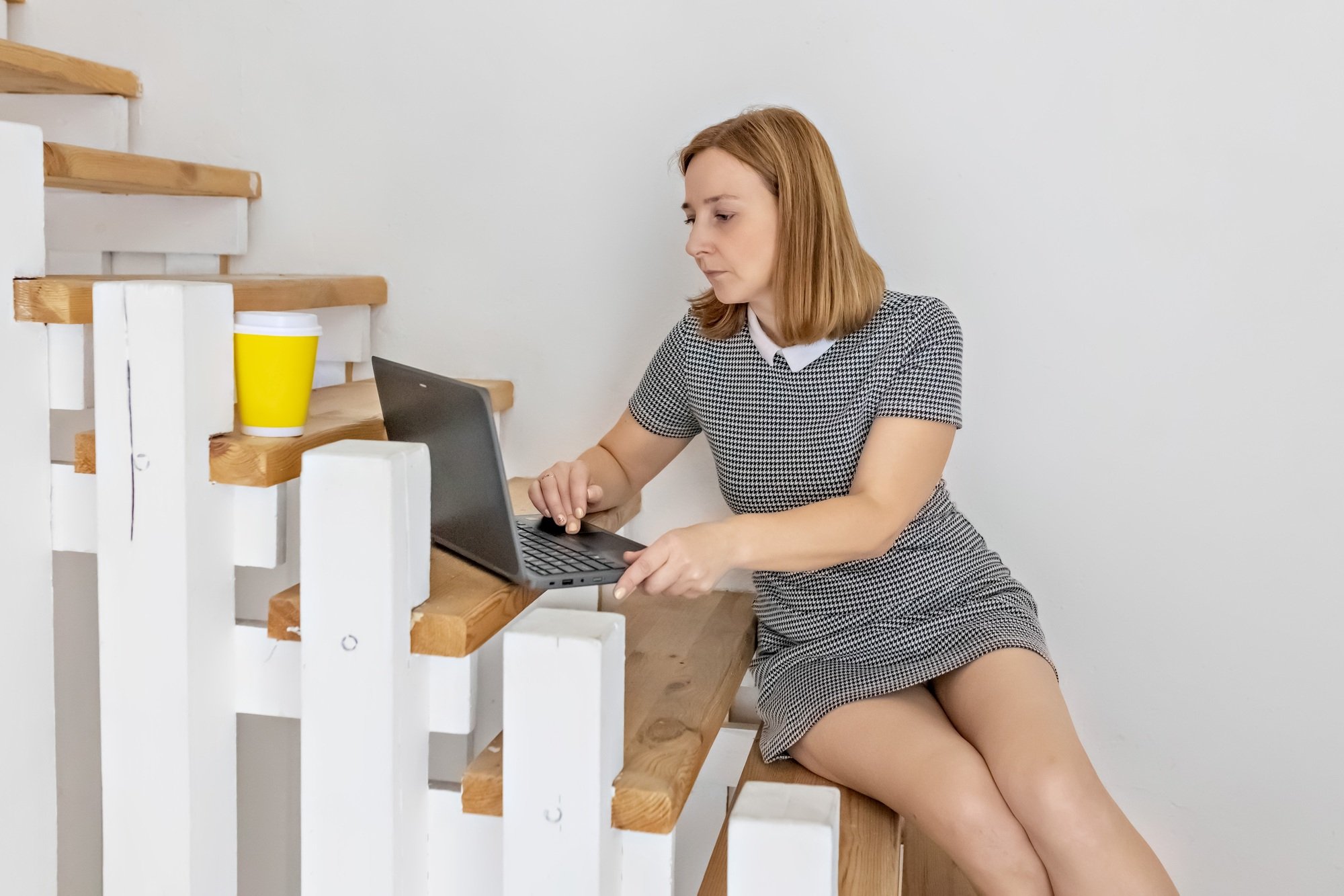 Business Young woman with laptop is working on the stairs at home. Business woman. Work from home, r