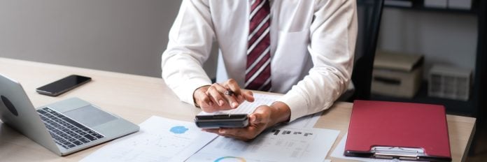 Businessman use calculator to calculate cost of project and checking marketing document of startup
