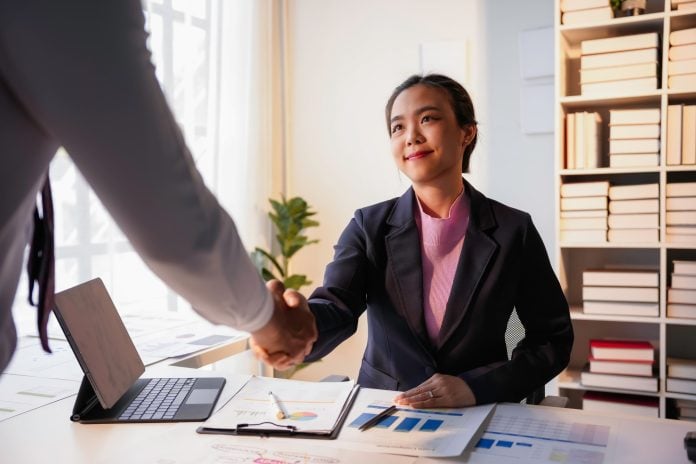 Businesswoman is shaking hands with her partner after closing a deal at the office