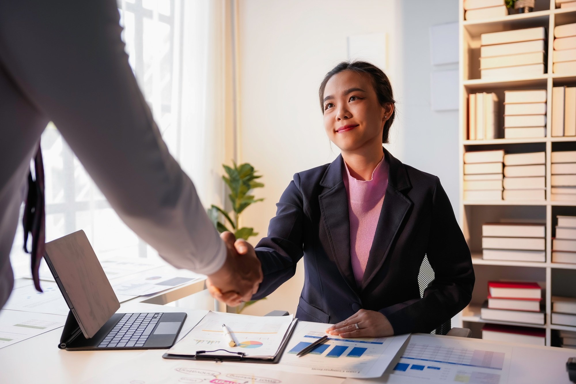 Businesswoman is shaking hands with her partner after closing a deal at the office