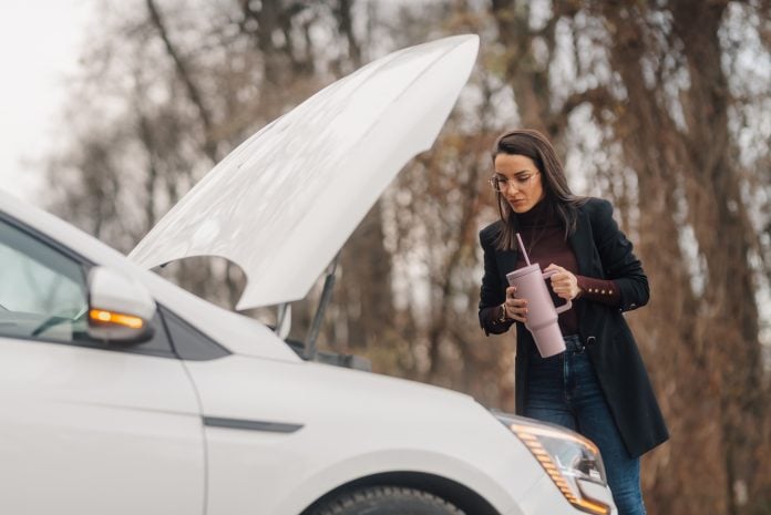 Businesswoman waiting for roadside assistance drinking from reusable cup