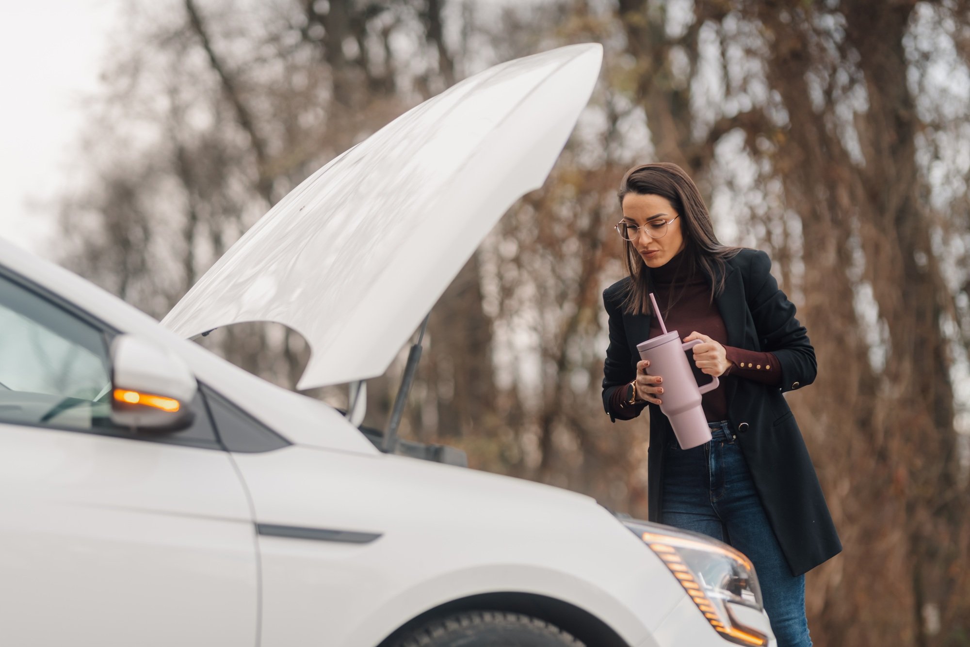 Businesswoman waiting for roadside assistance drinking from reusable cup