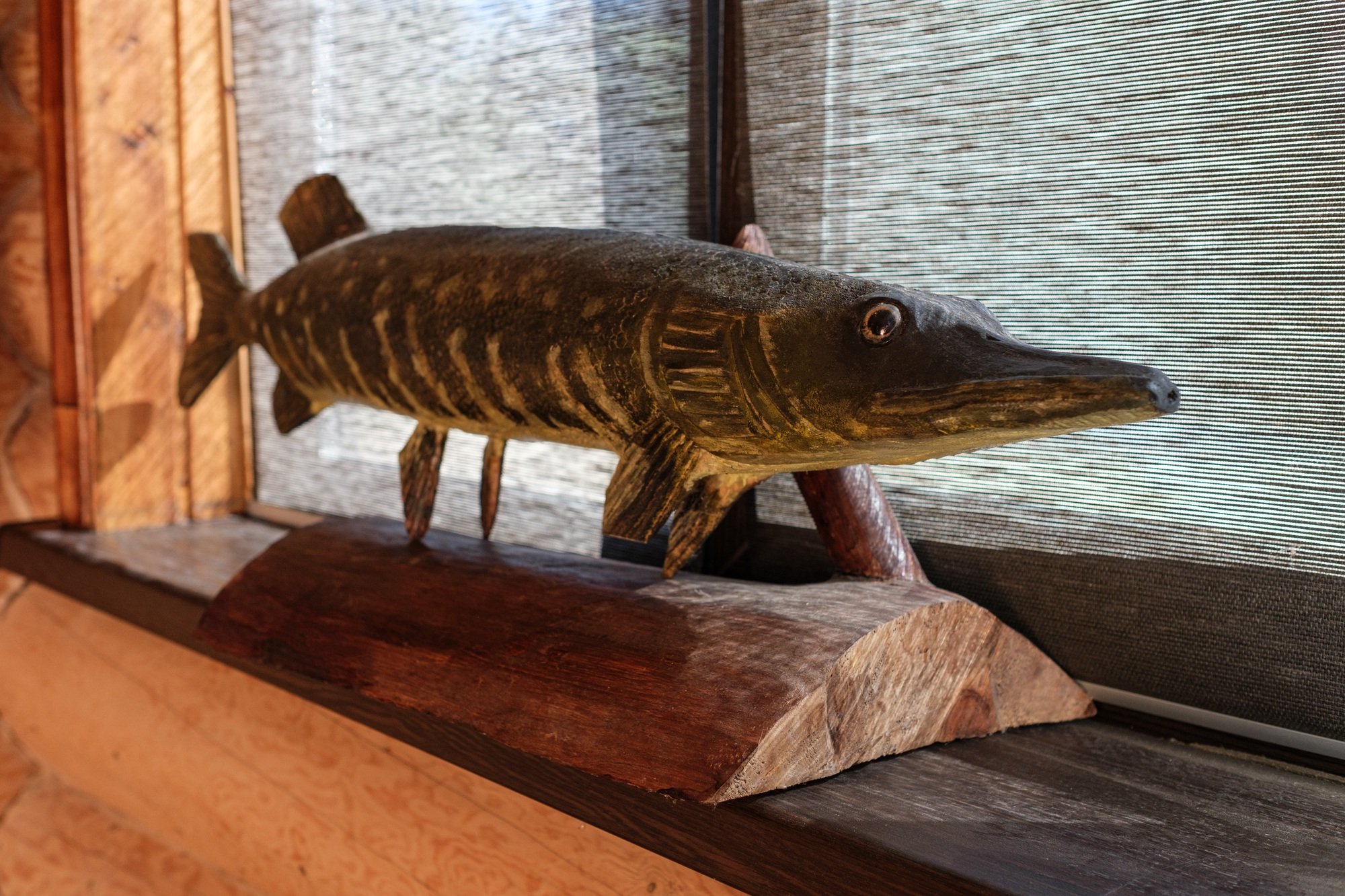 Carved wooden fish pike on a stand. DIY concept.