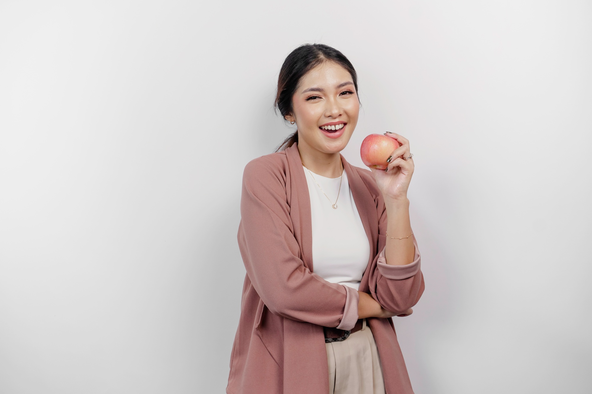 Cheerful Asian woman employee is holding an apple for diet and weight loss.