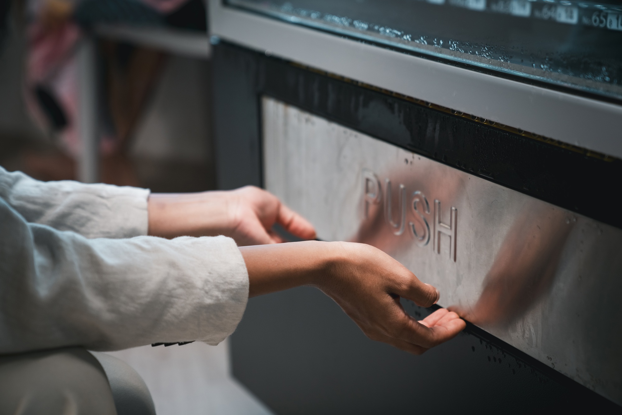 Close up hand of woman pushing button on vending machine for choosing a snack or drink.