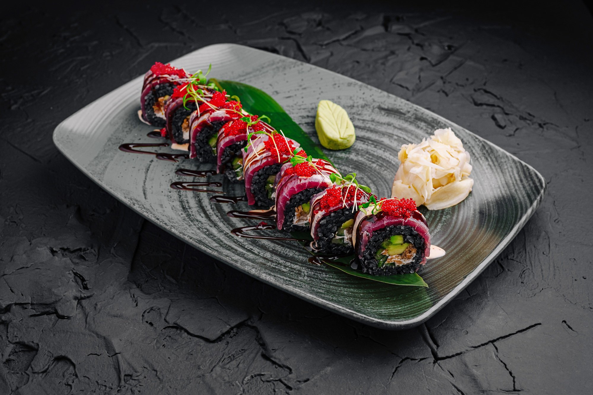 Colorful sushi rolls served on a decorative plate with garnishes in a modern restaurant setting