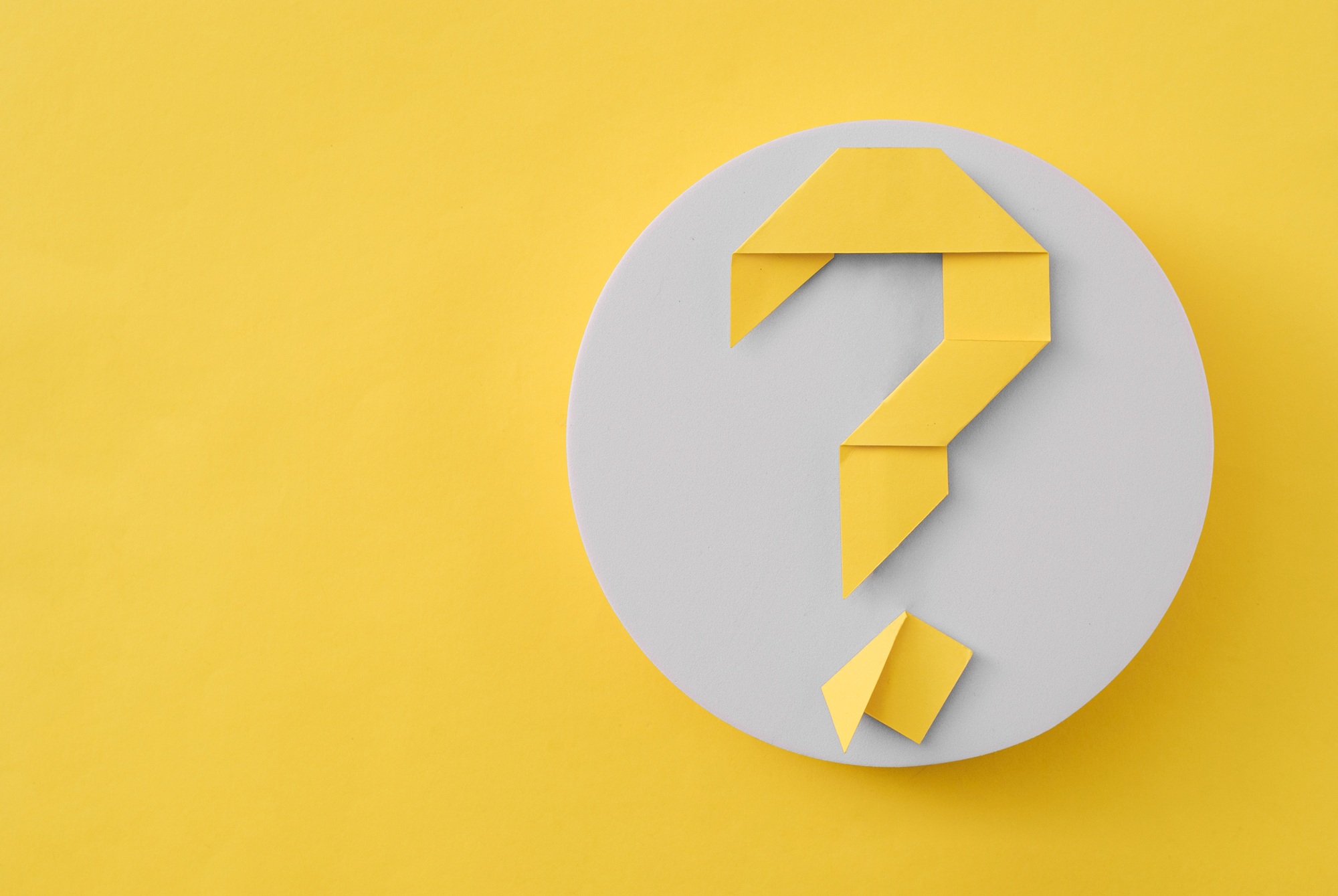 Colorful yellow origami question mark on a circle