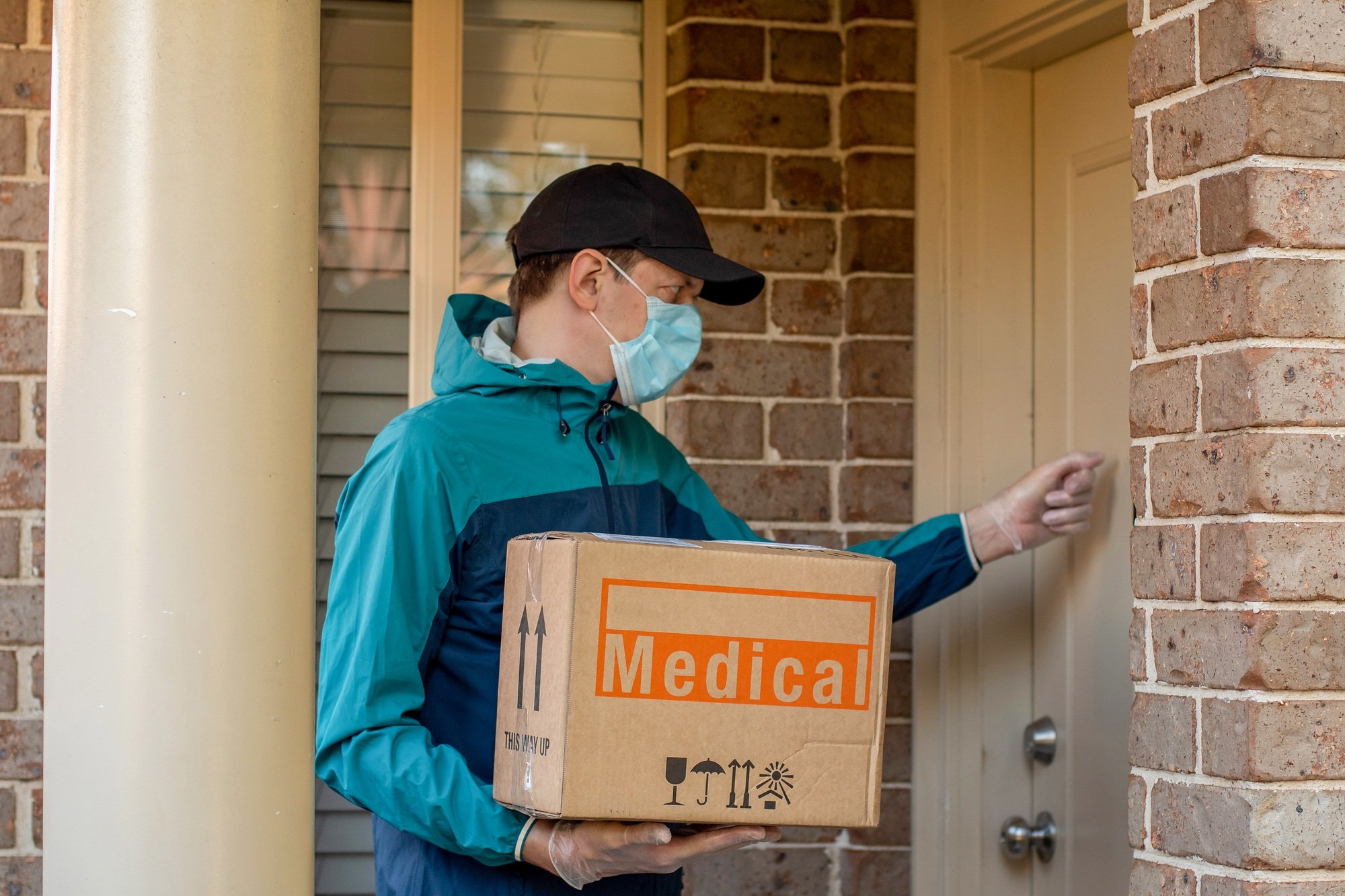 Contactless delivery during COVID-19 pandemic lockdown concept. Courier wearing mask at the door