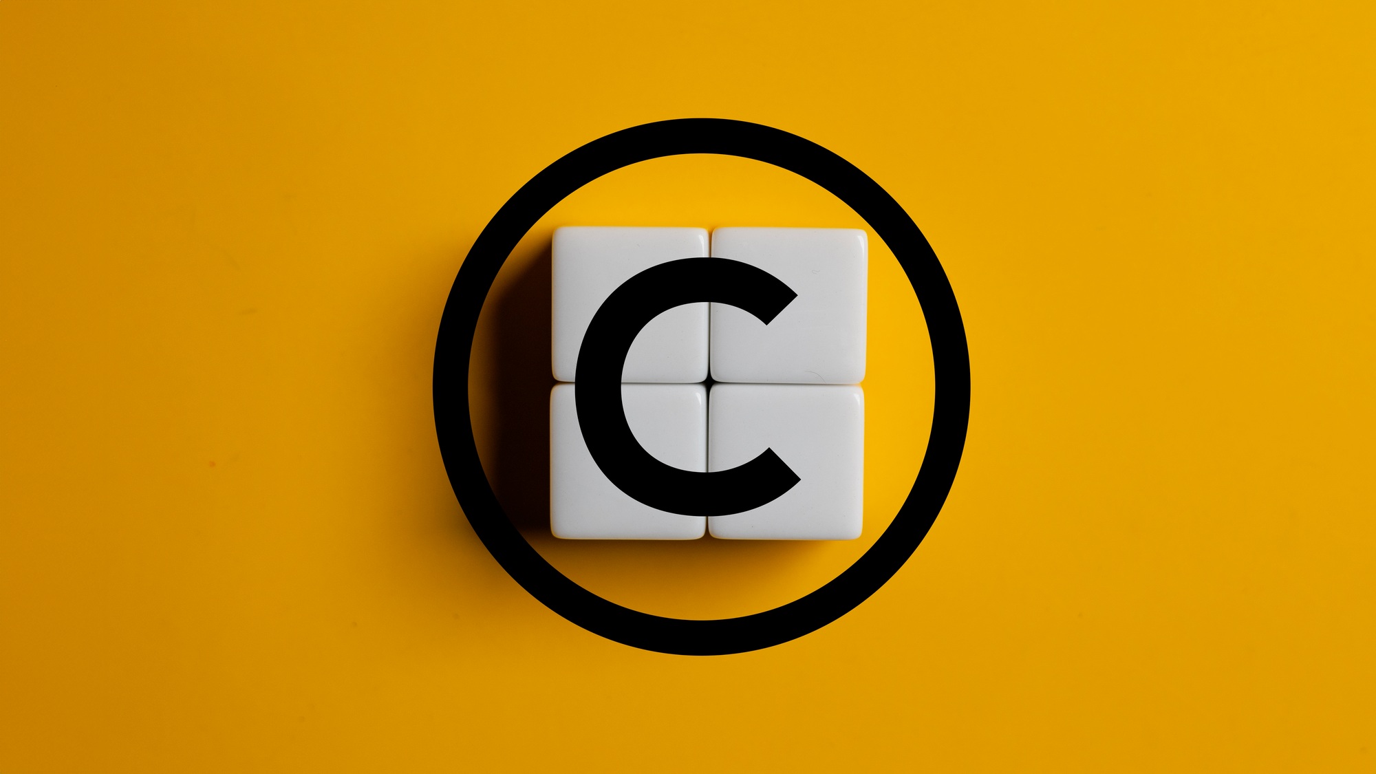 Copyright symbol on wooden blocks on yellow background. Concept of patenting or copyright protection
