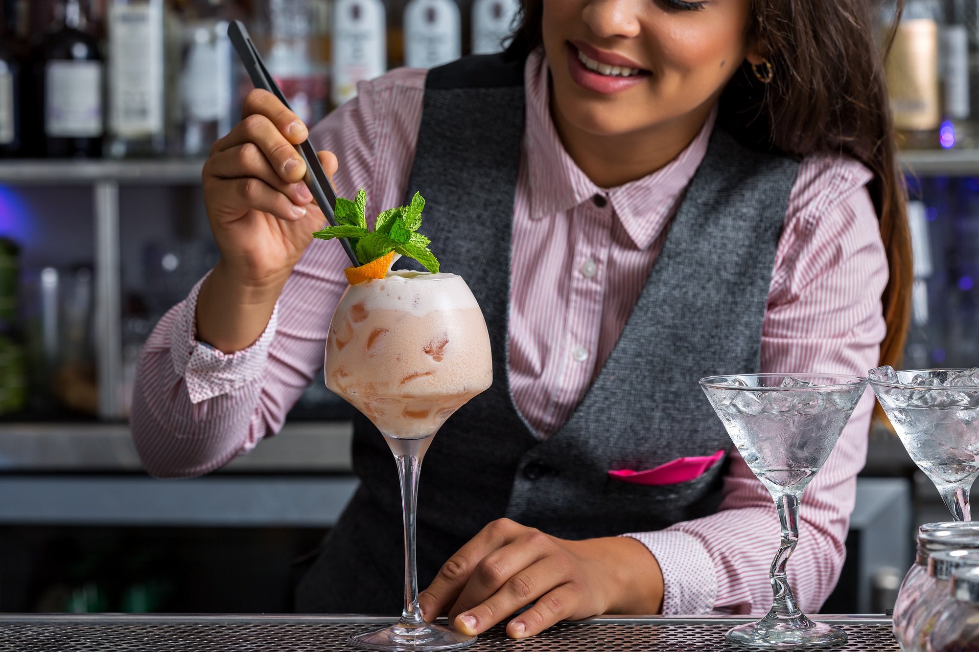 Crop female bartender decorating cocktail