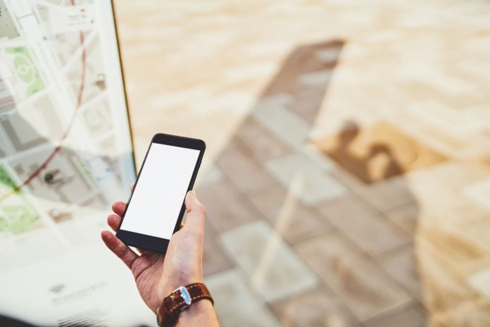 Cropped image of male hand holding smartphone with mock up screen copy space area for advertising