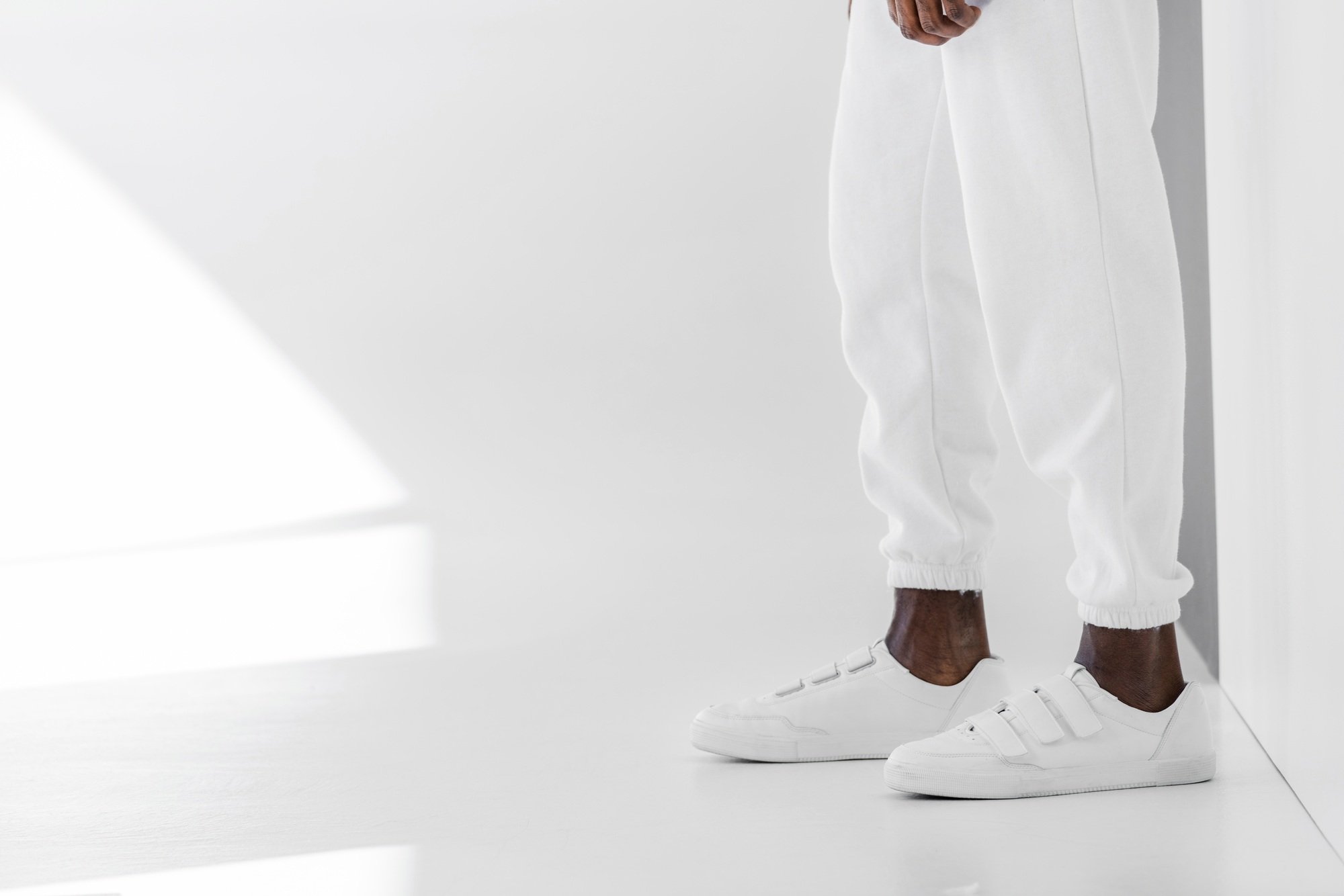 cropped image of stylish african american man in white clothes and gumshoes on white