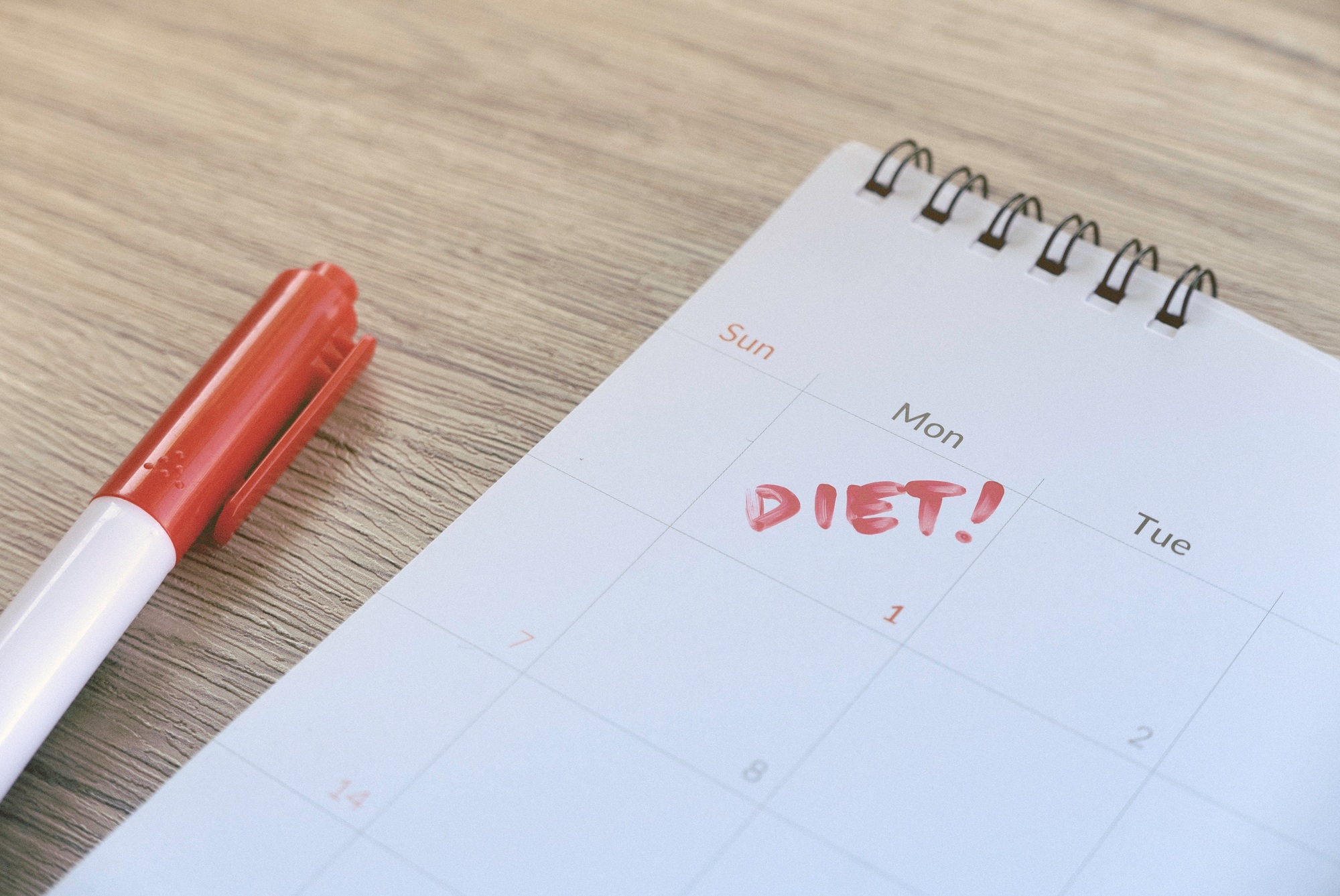 Diet Plan Reminder on Calendar with Red Pen on Wooden Table