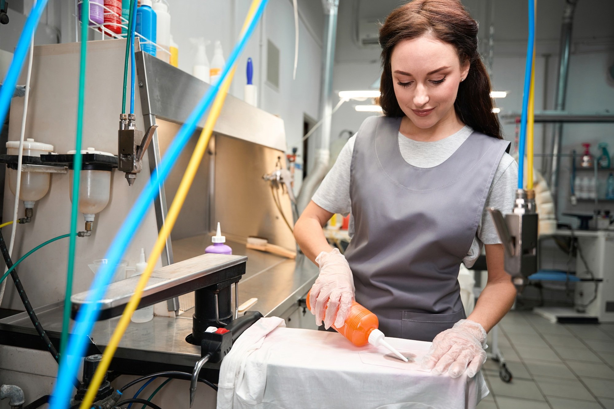 Dry-cleaning operator adding solvent to spots, treating clothes before cleaning