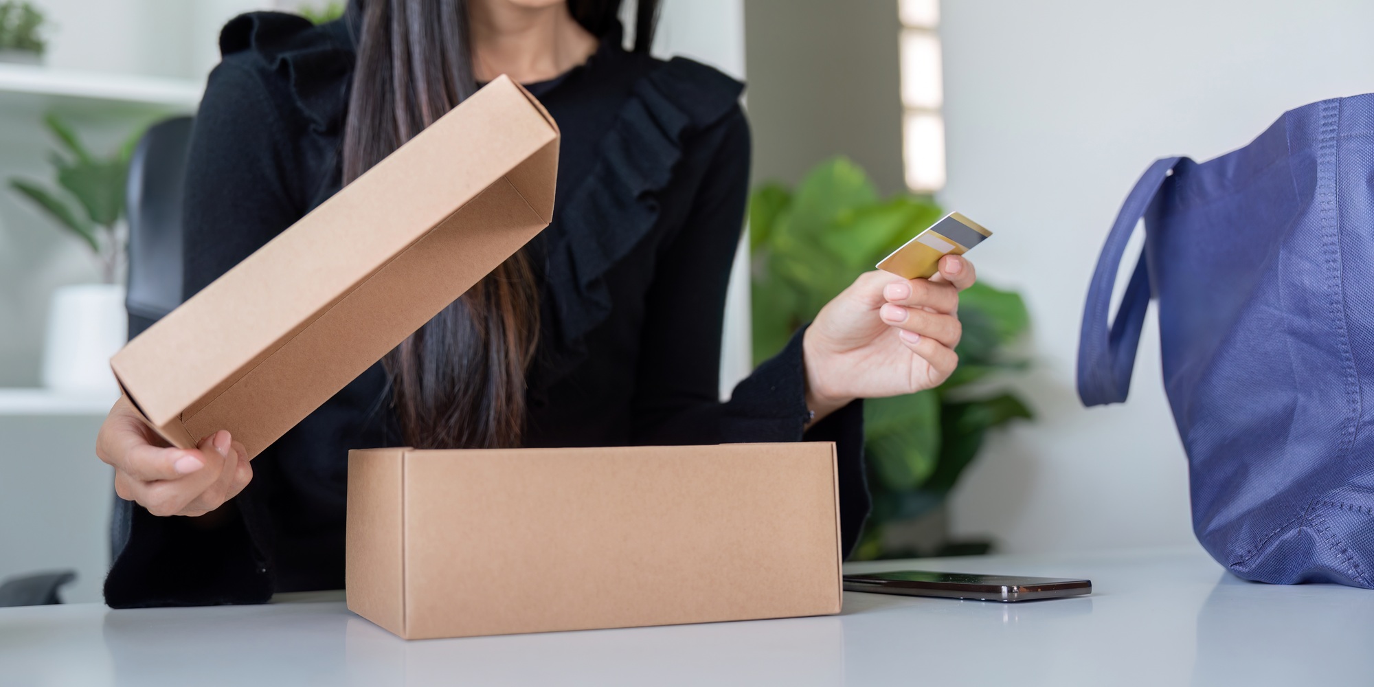 Eager Shopper Unboxing Package with Credit Card in Hand