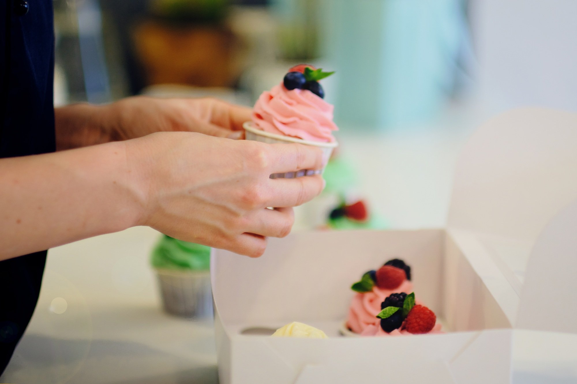female cook is packing in a box of cupcakes. small business concept.