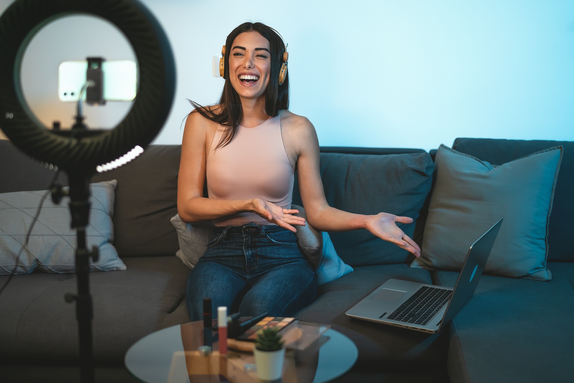 Female influencer vlogging online with smartphone cam and laptop from home