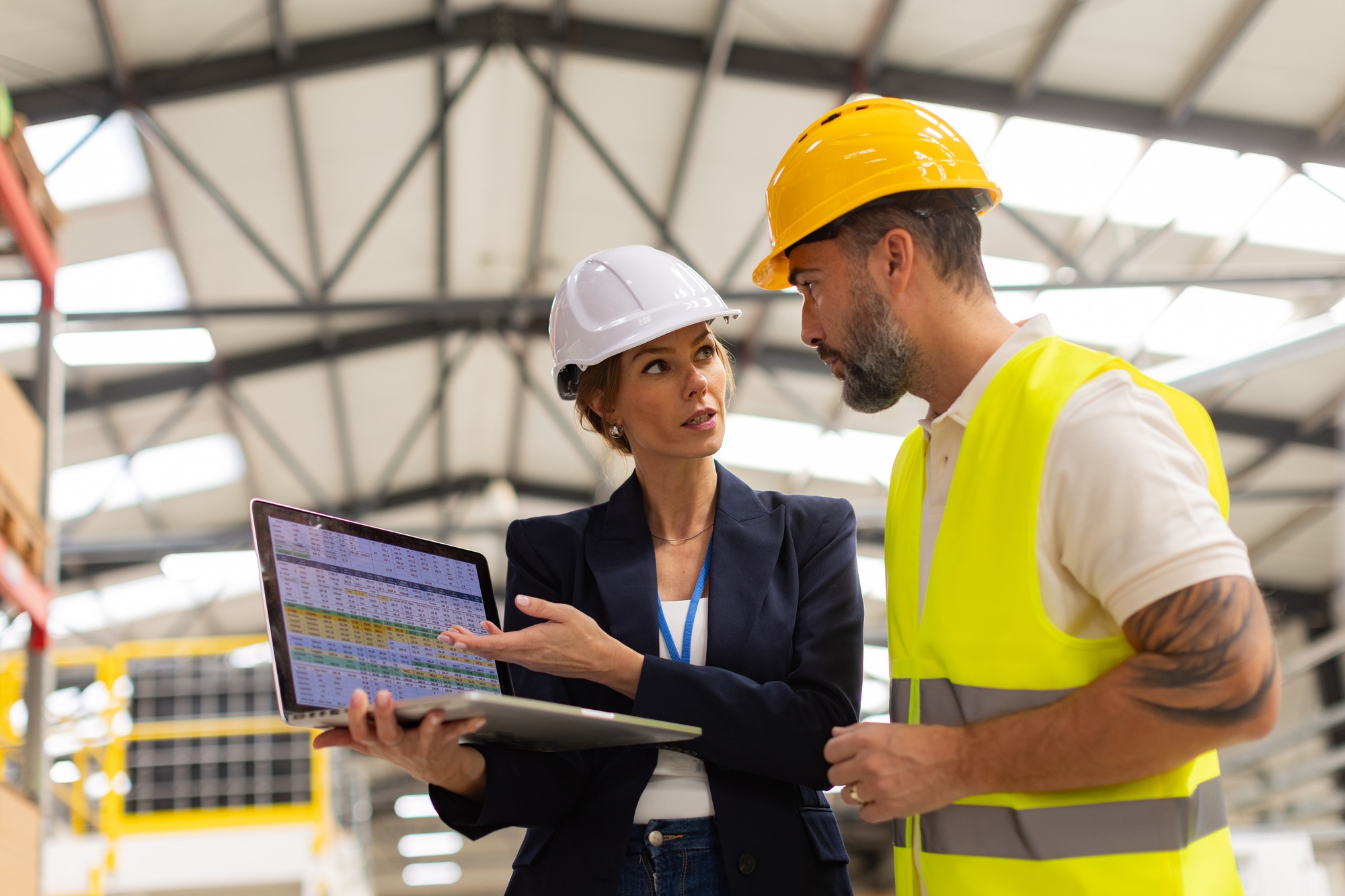Female manager talking with foreman, checking production plan on notebook. Woman quality controller