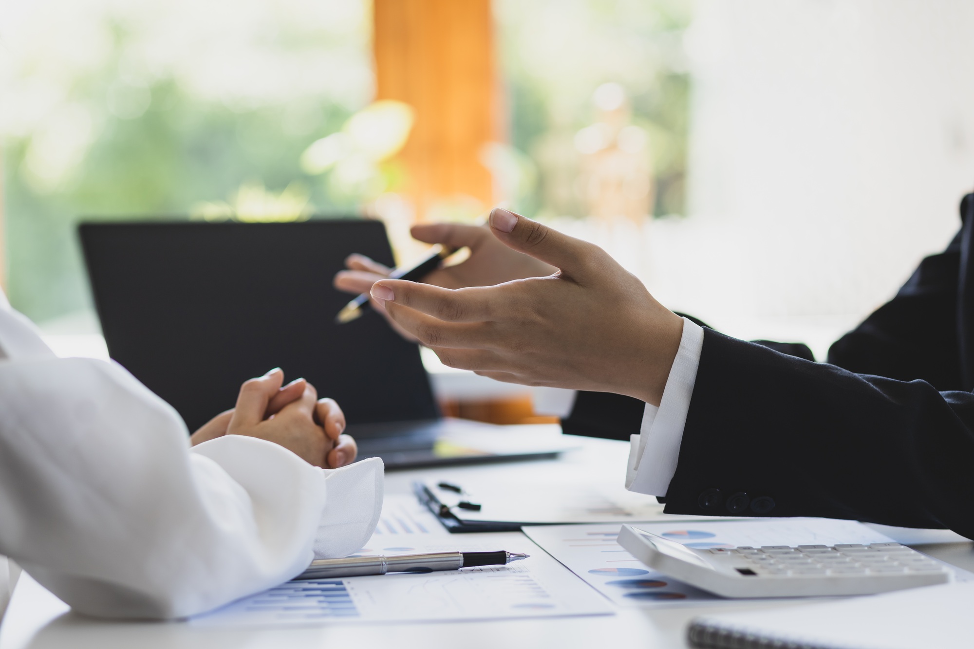 Financial advisor discussing business management planning with businesswoman in office.