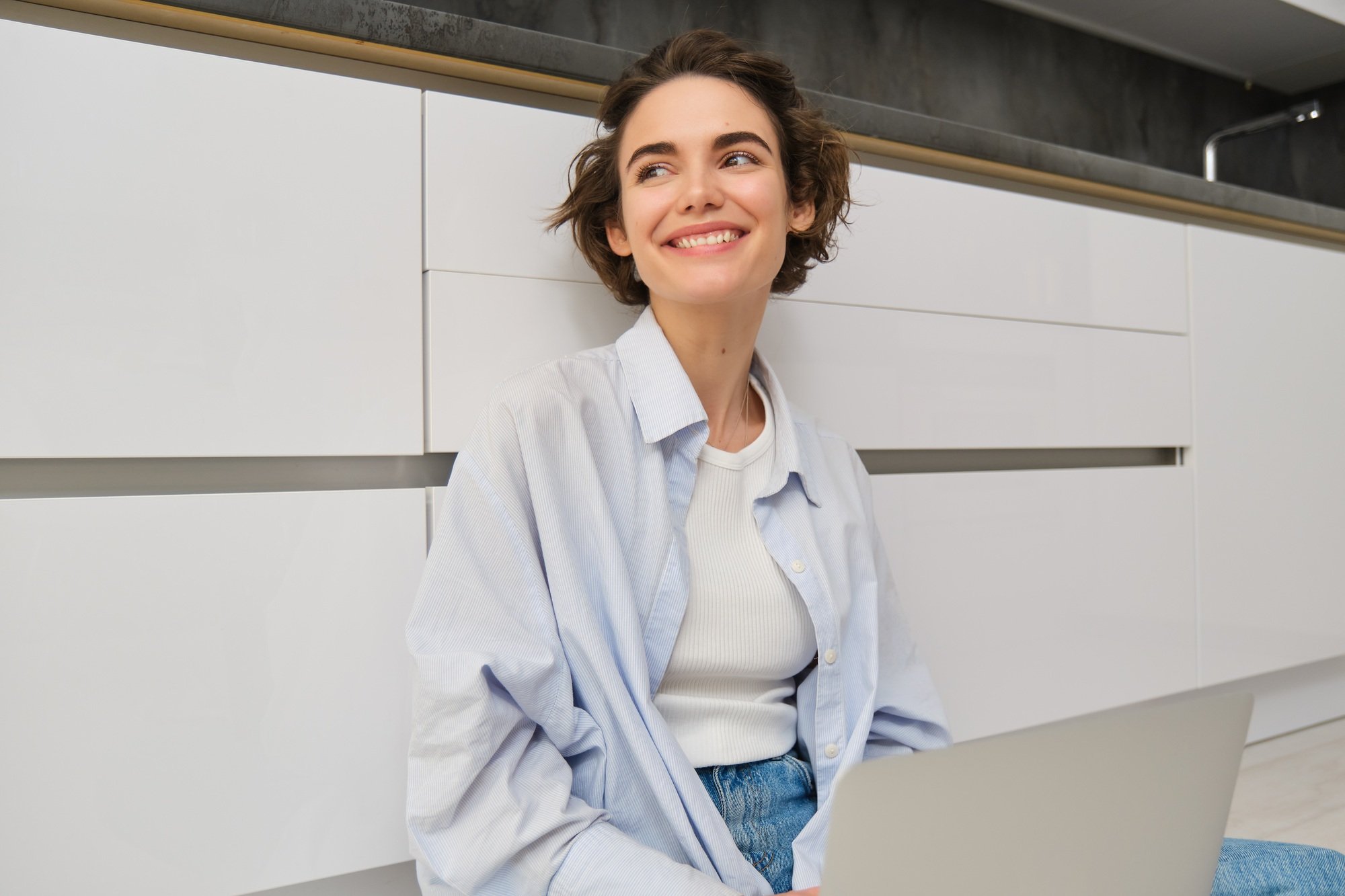 Freelance and lifestyle concept. Young woman sits on floor with laptop, works from home, sets up