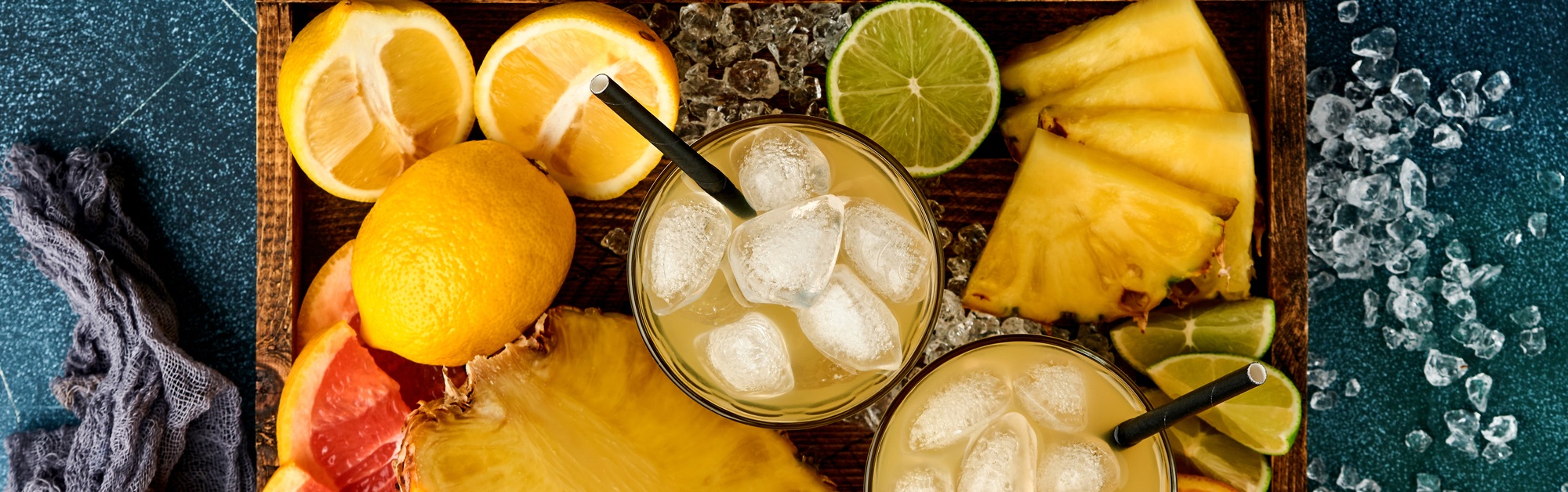 Fresh juice pineapple with ice and variety sliced ripe of color tropical fruits grapefruit, orange,