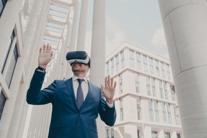 Futuristic image of happy businessman using virtual reality 3d goggles while standing outdoors