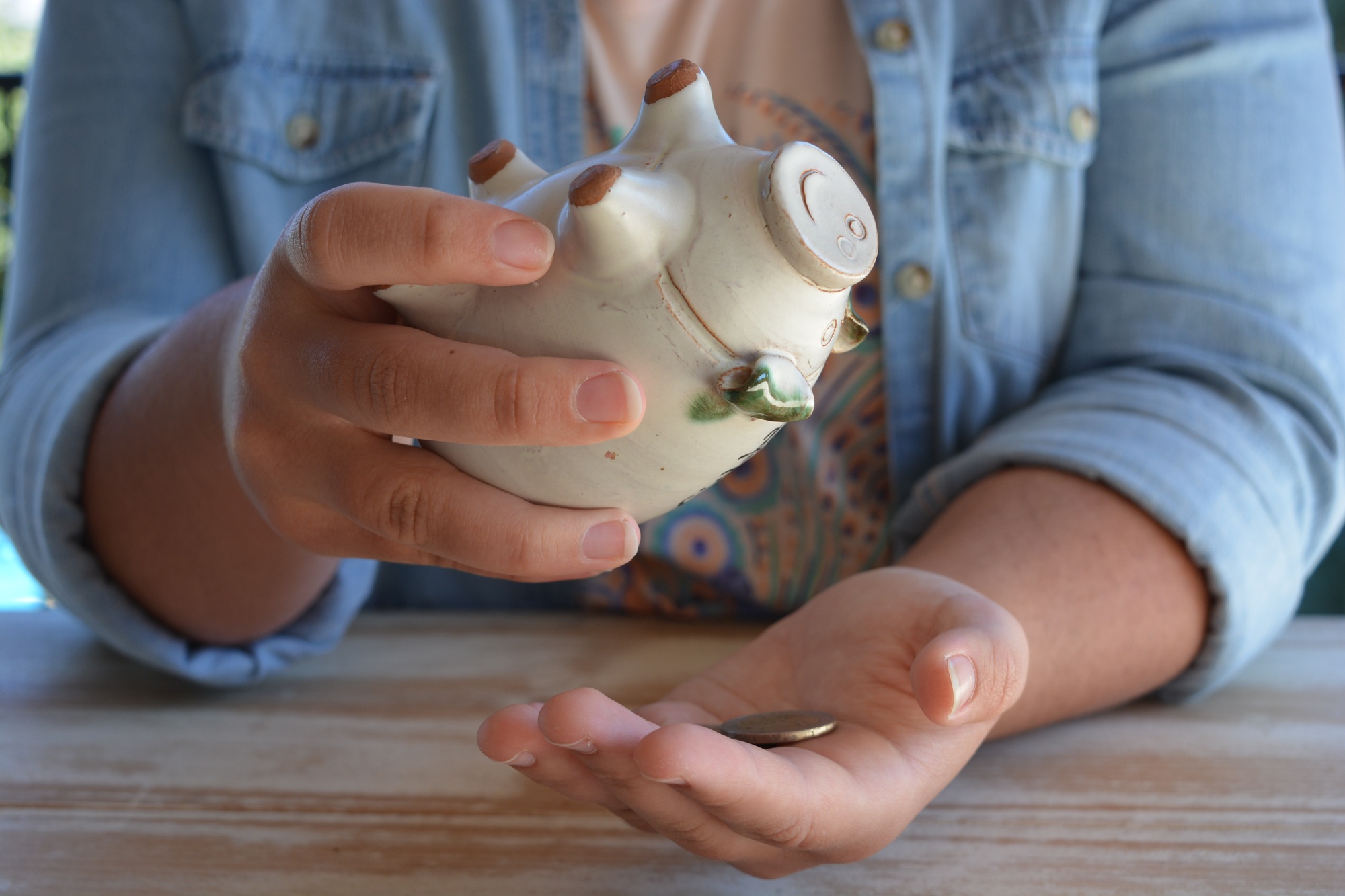 Girl tipping coins out of piggy bank into her hand, counting her money