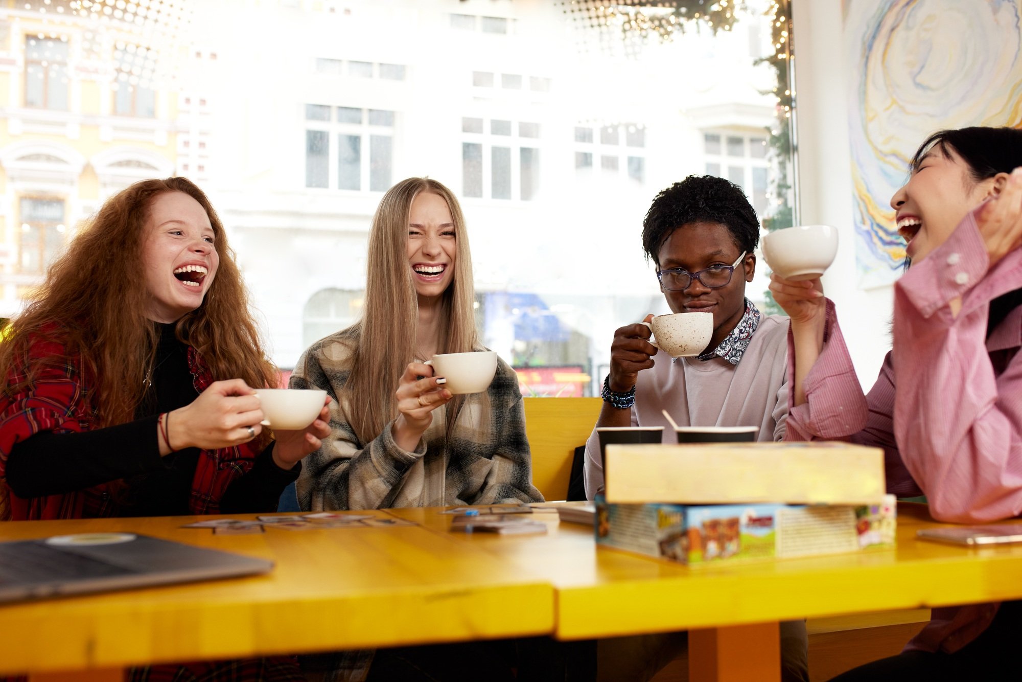 Group of multiracial young people sharing ideas and having friendly conversation during coffee break
