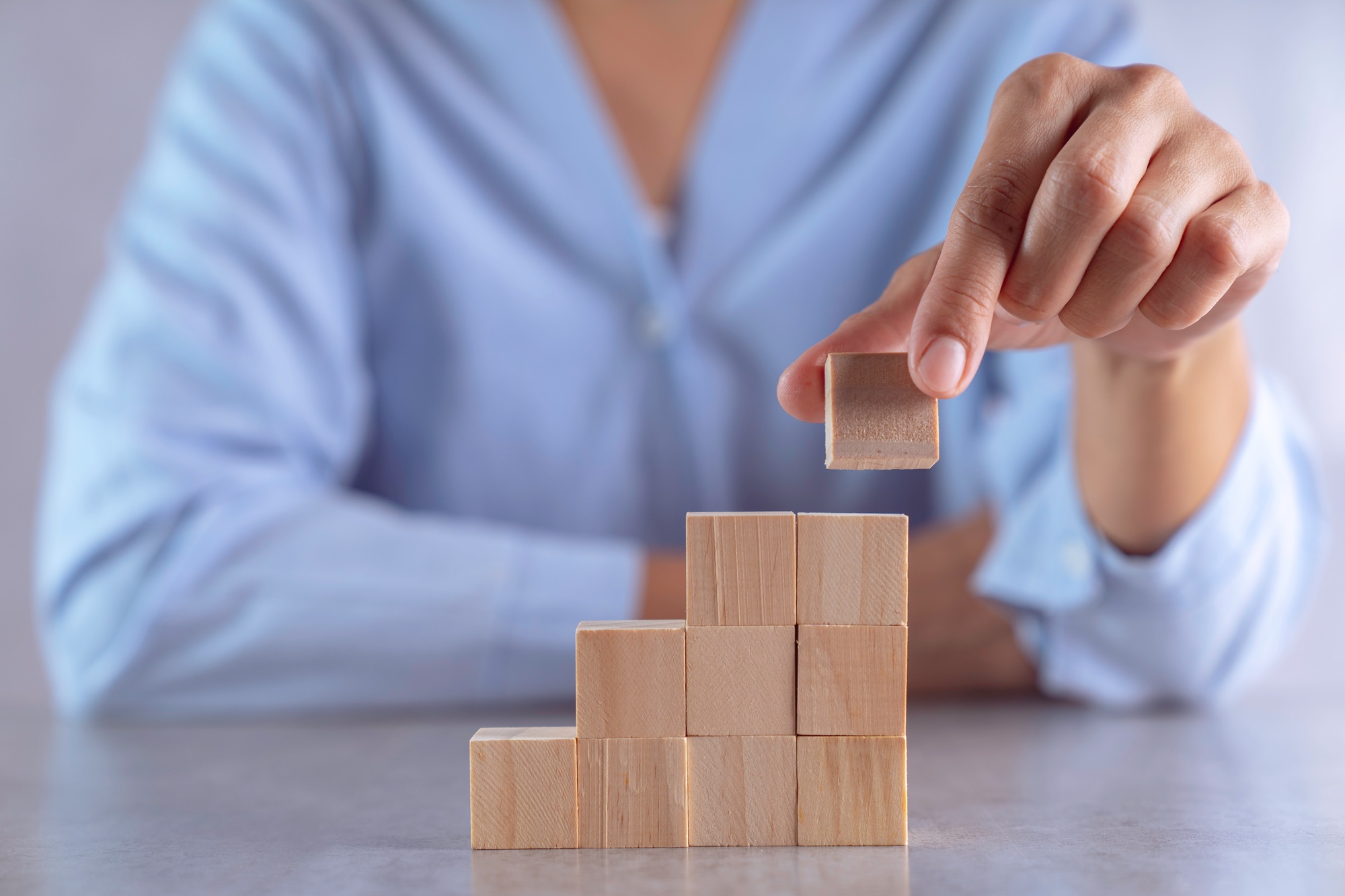 hand arranging wood cube stacking as stair step shape, mock up for create symbol or logo, business g