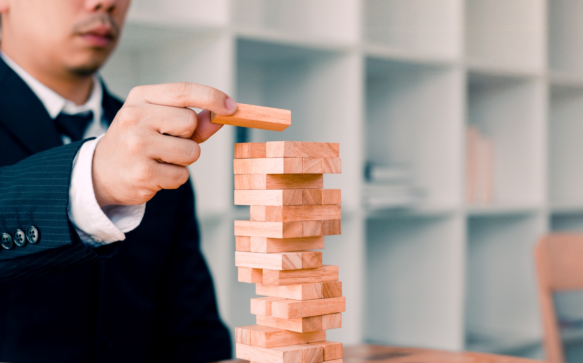 Hand of businessman playing wood blocks stacks game with planning strategy of project management.