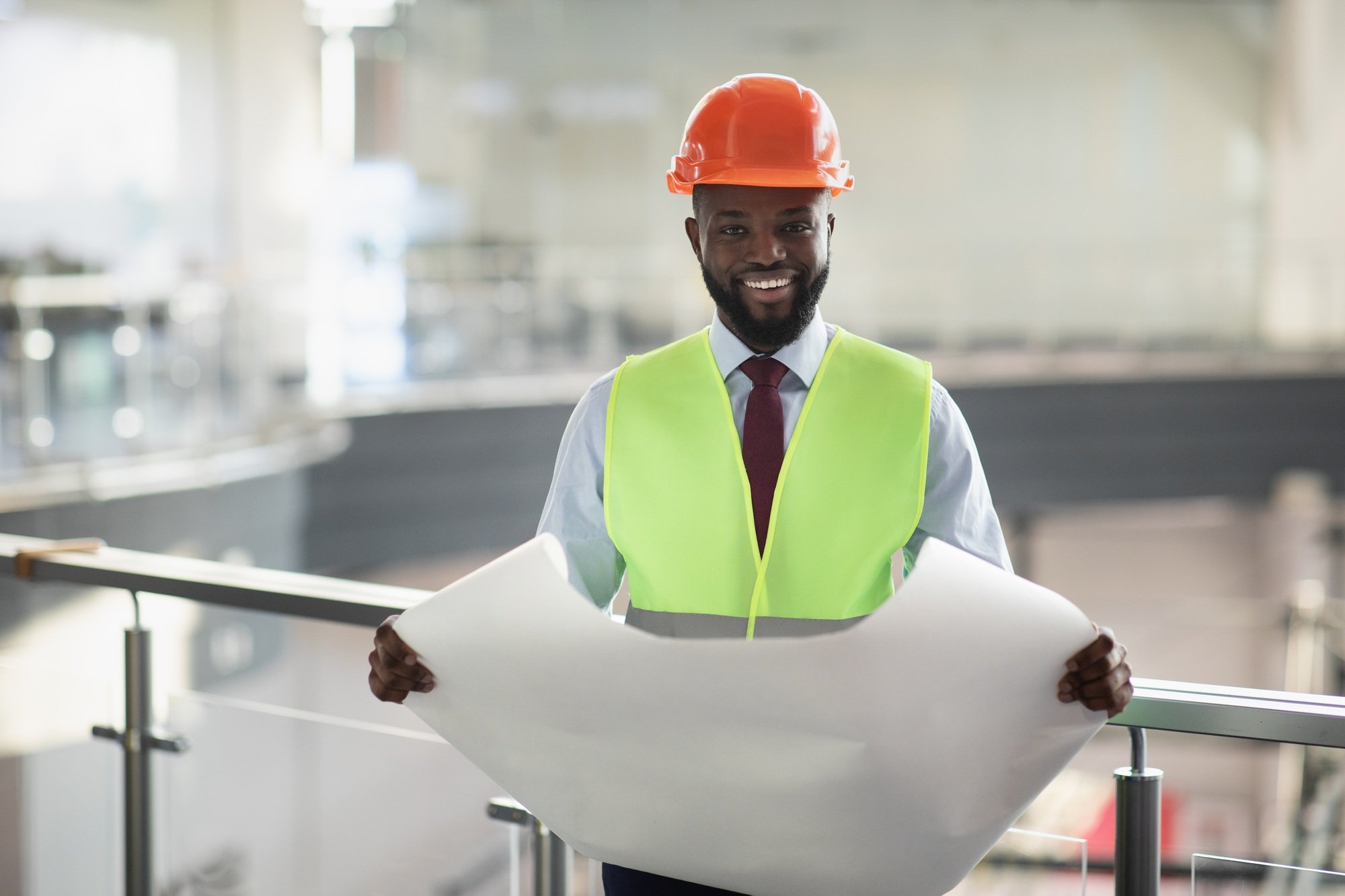 Happy african american man engineer holding paper drawing template