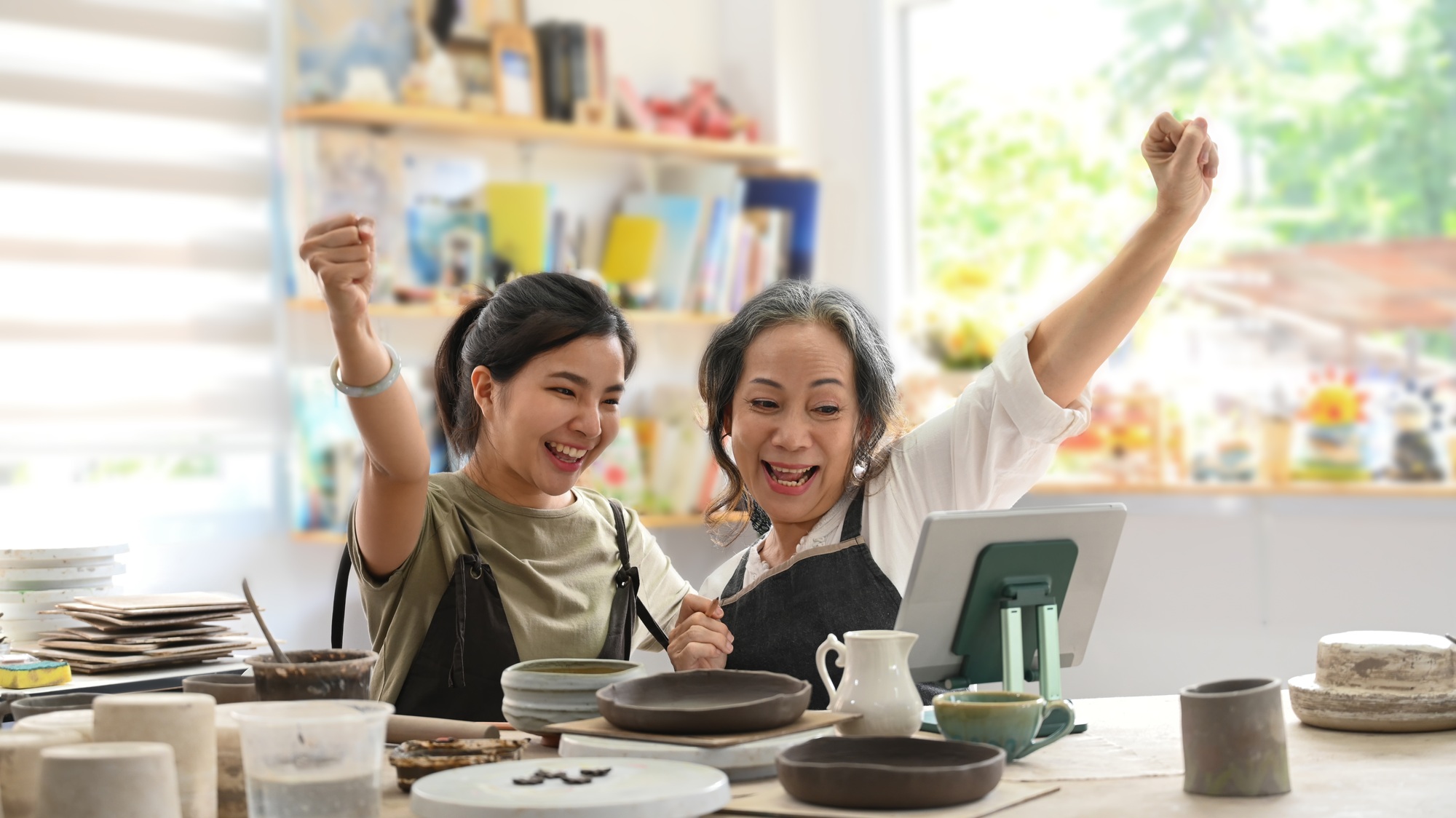 Happy craft pottery shop owners celebrating for sales success after checking order.