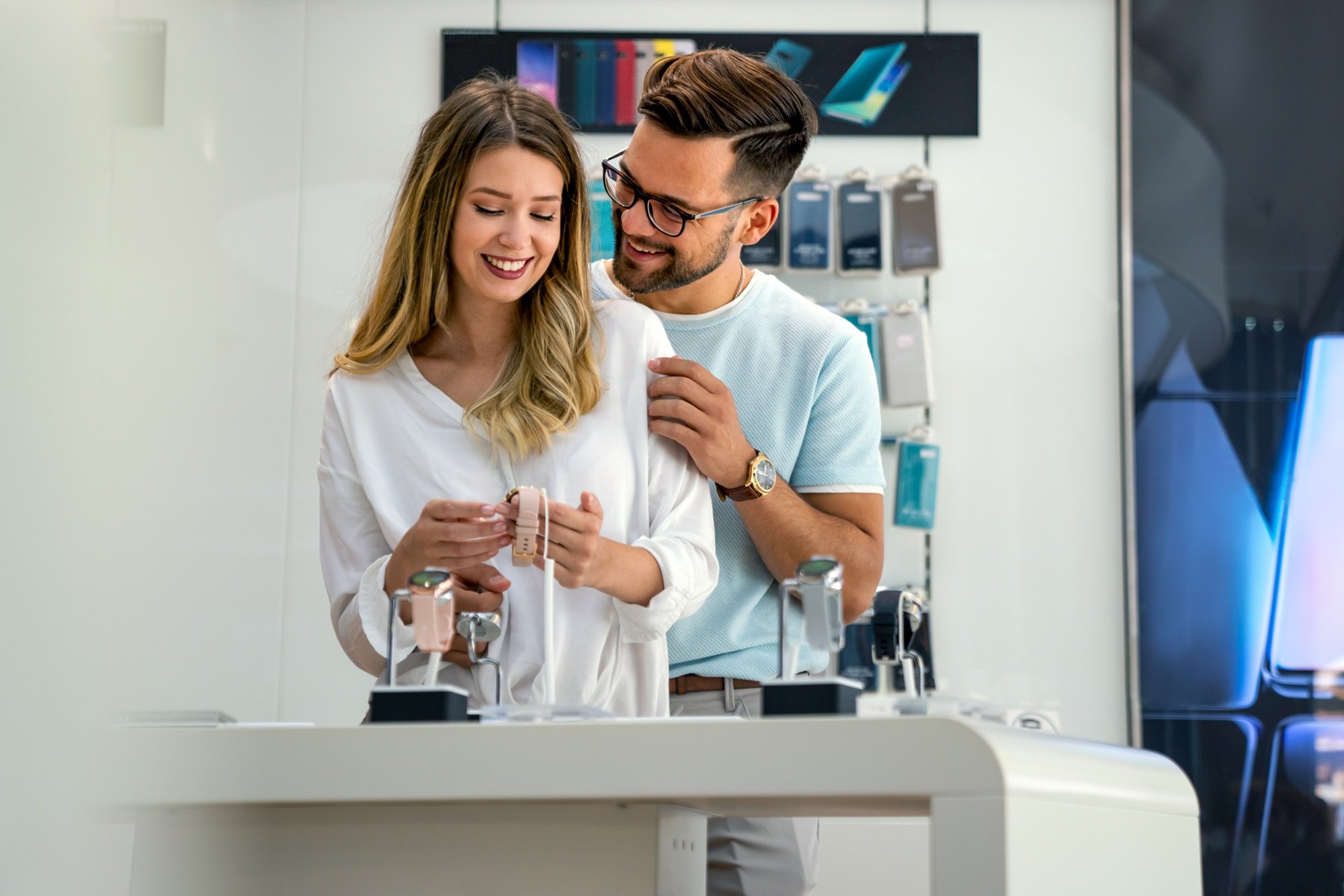 Happy young people buying new digital gadgets in store. Tecgnology smart watch shopping concept