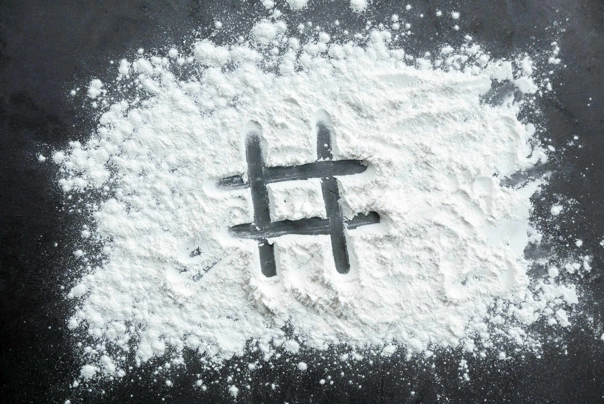 Hashtag symbol written on a sprinkled powder on teh table.