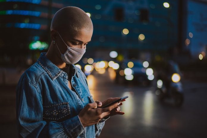 Image of a young woman using mobile phone on the street.