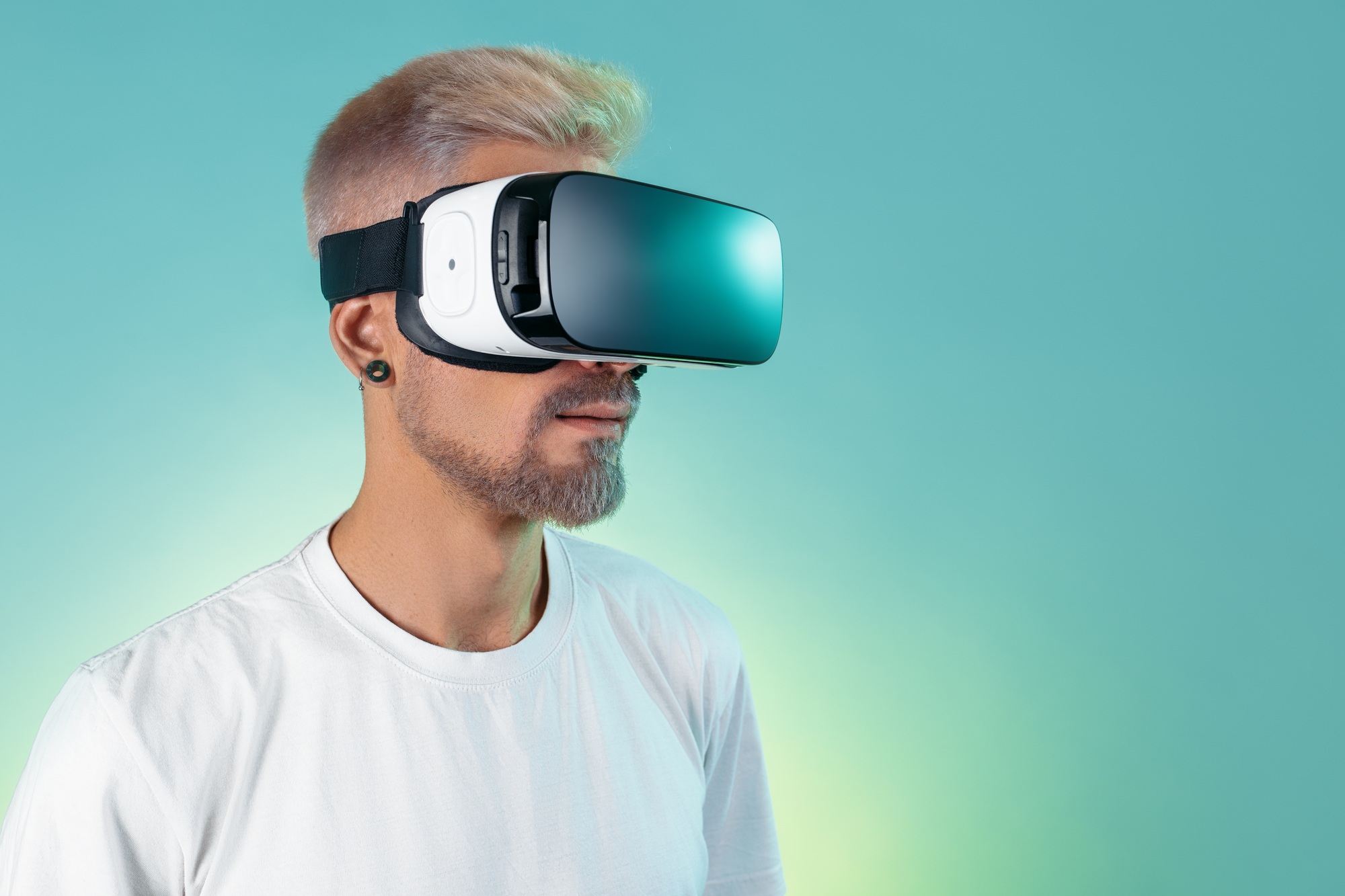 Image of bearded hipster man wearing virtual reality goggles in studio in neon lights.