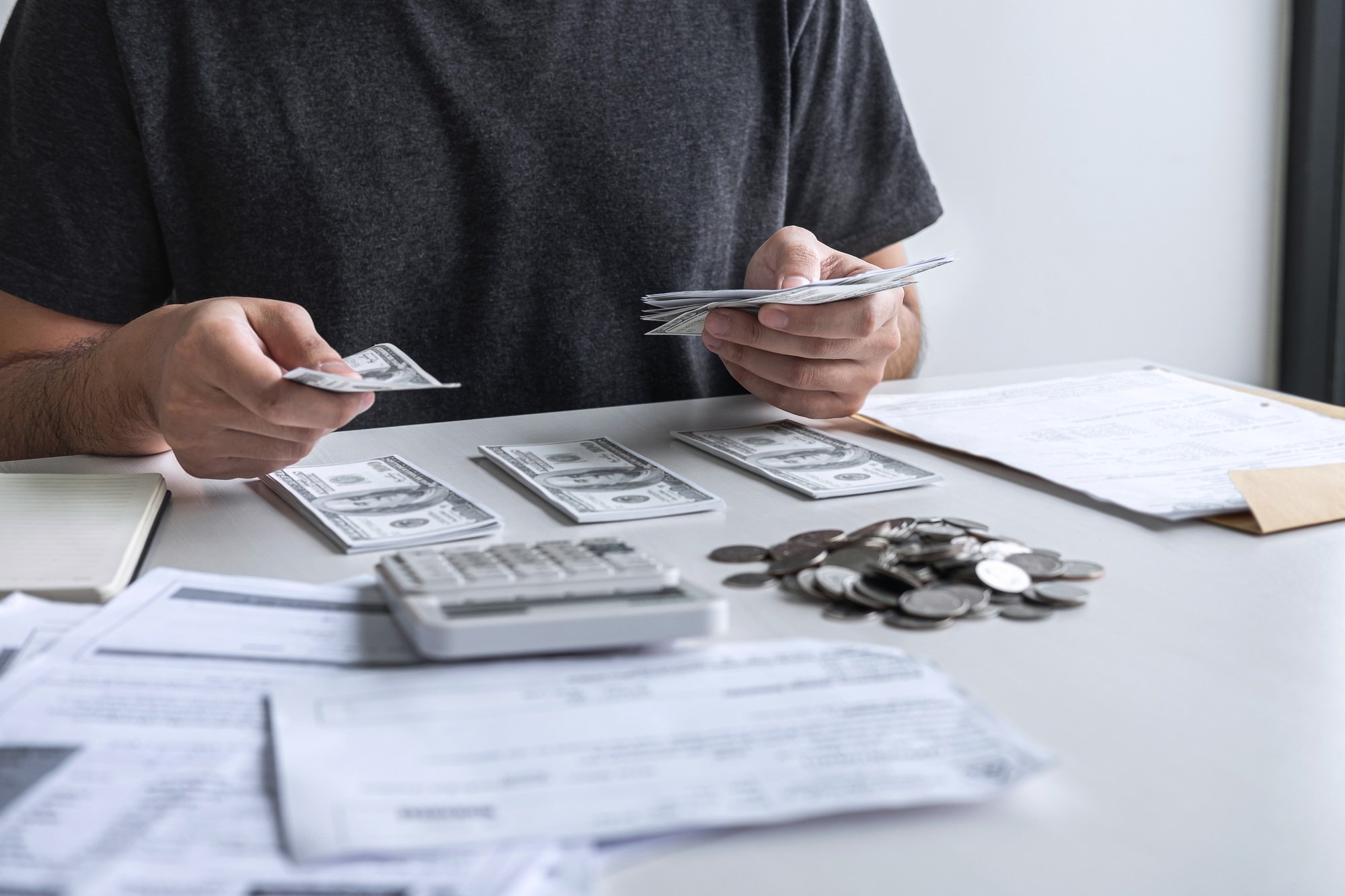 Images of stacking coin pile and Husband using calculator to calculating expenditure receipt bills