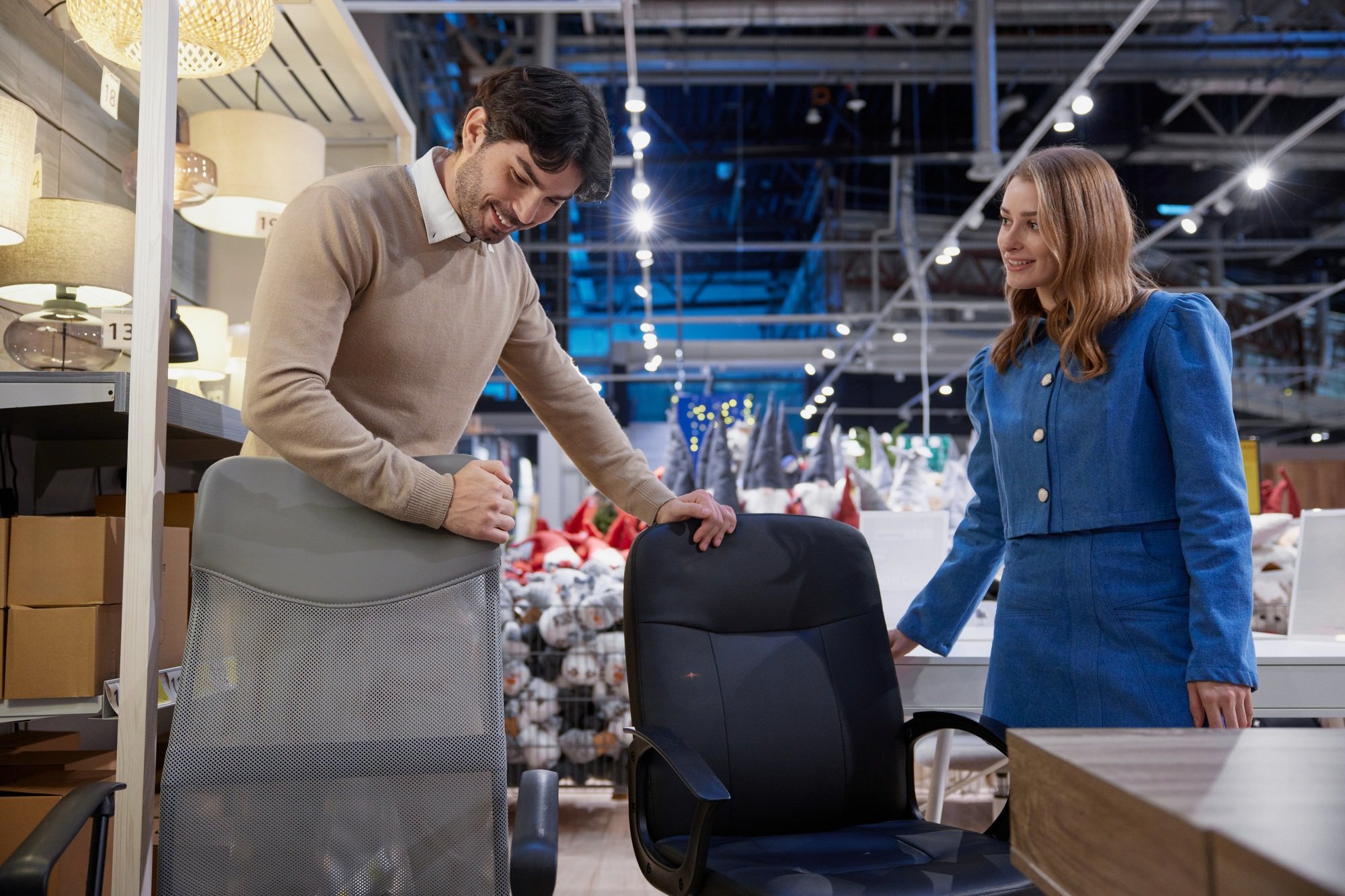 In furniture store man and woman engage in discussion about different ergonomic office chair options