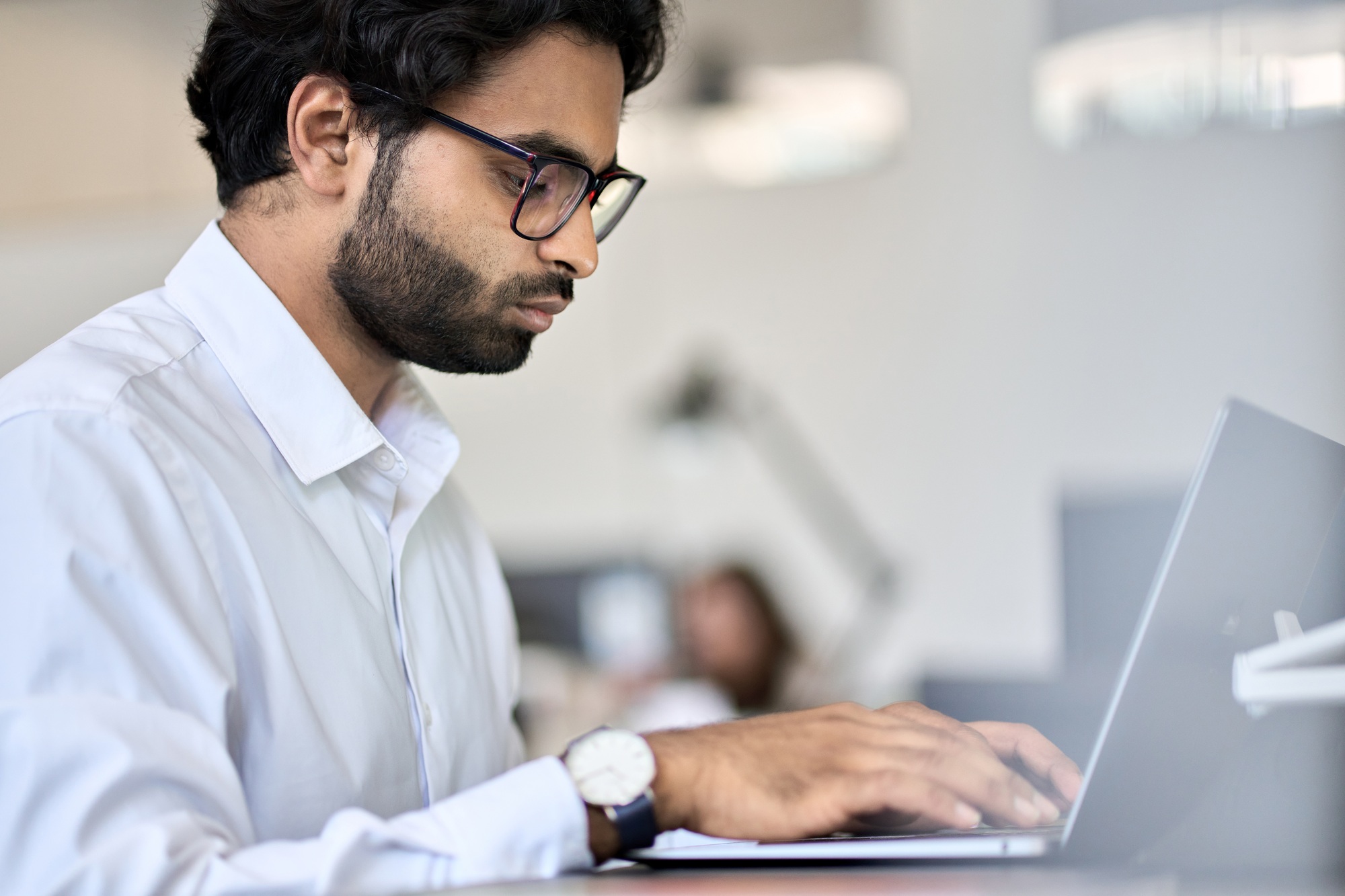 Indian business man software engineer using laptop computer working in office.