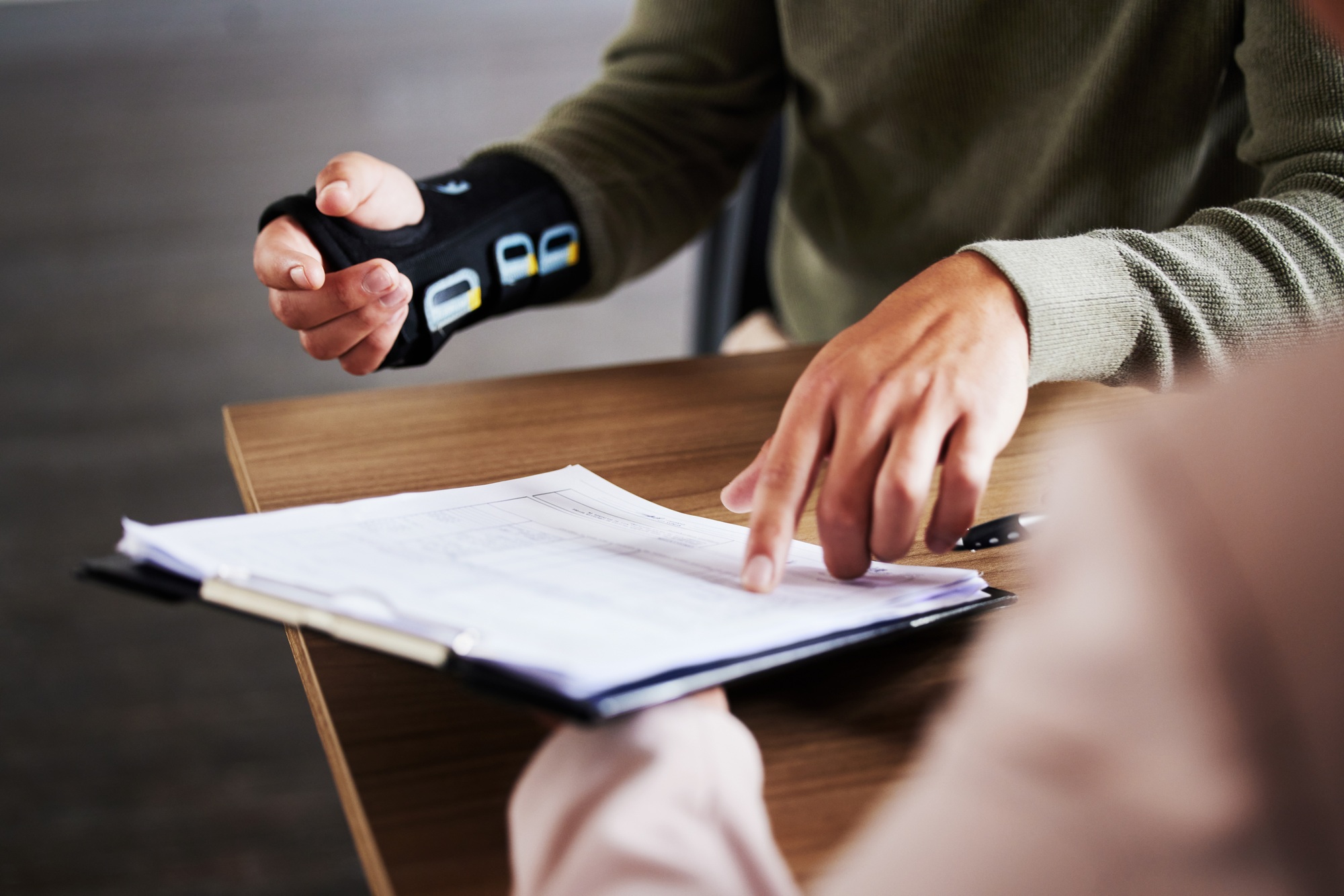 Injury, compensation and man hands with insurance documents, legal contract and paperwork. Disabili