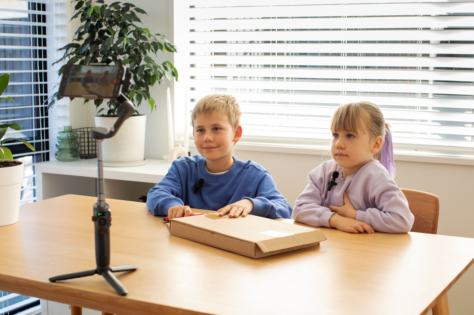 Kids recording an unboxing video for their vlog, smiling and excited as they reveal the contents