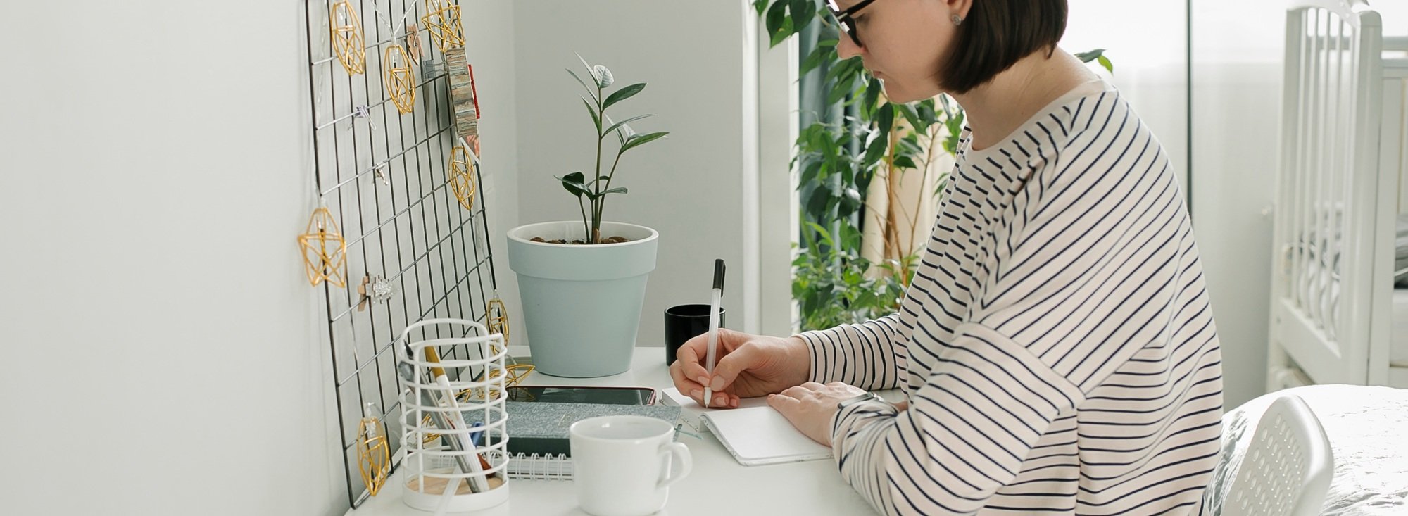 Long banner for design, web page. Young focused woman in striped sweater working at home.