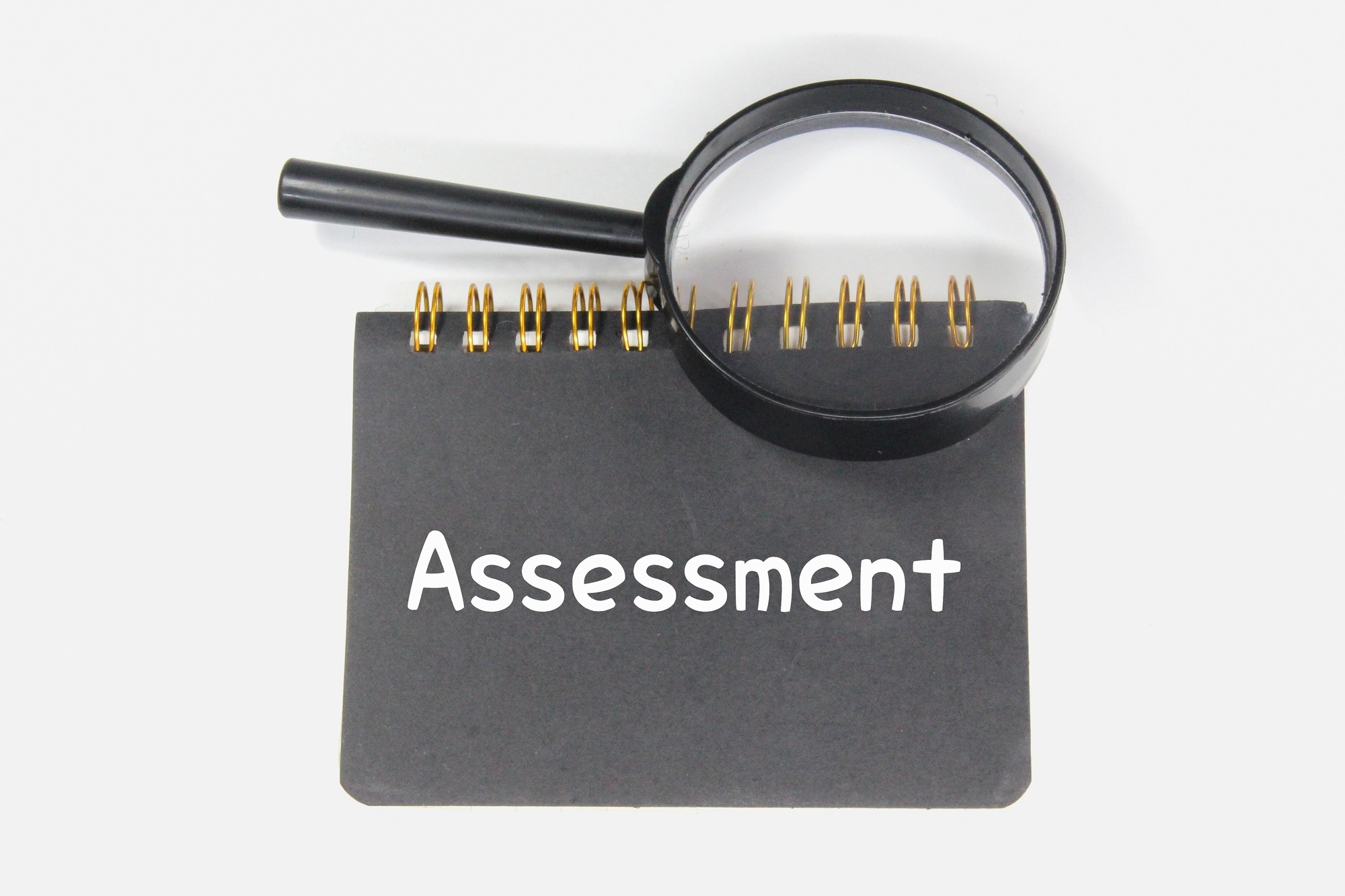 magnifying glass, notebook and word assessment